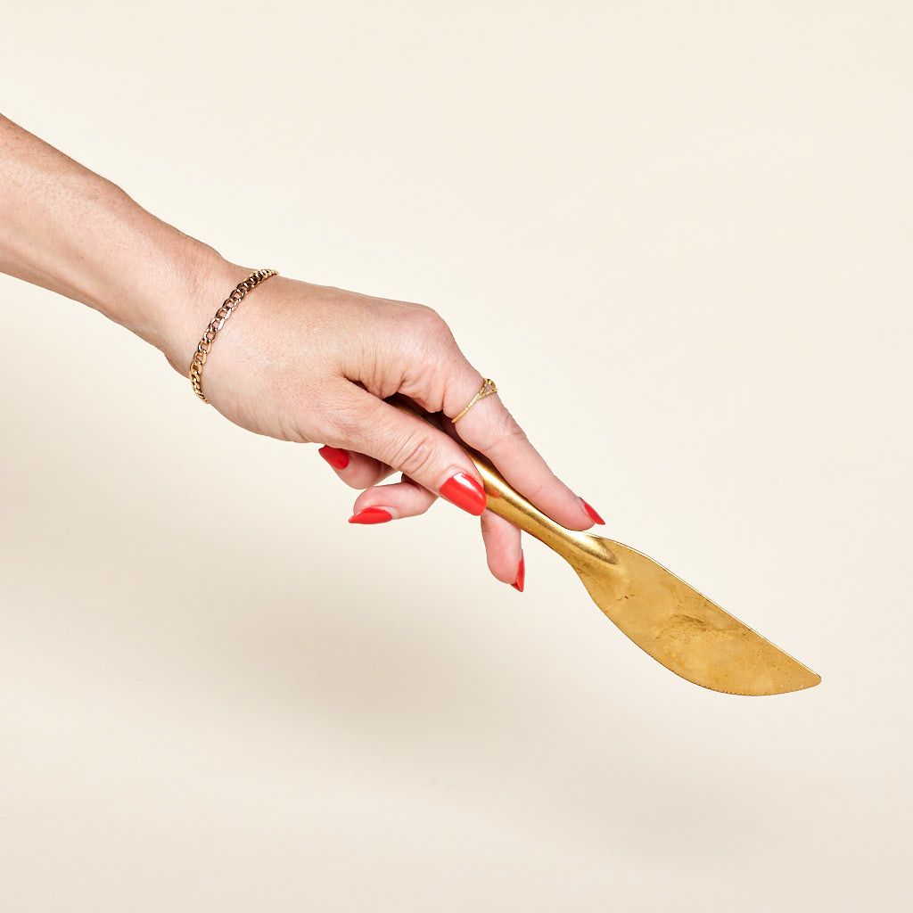 A hand holds a brass knife