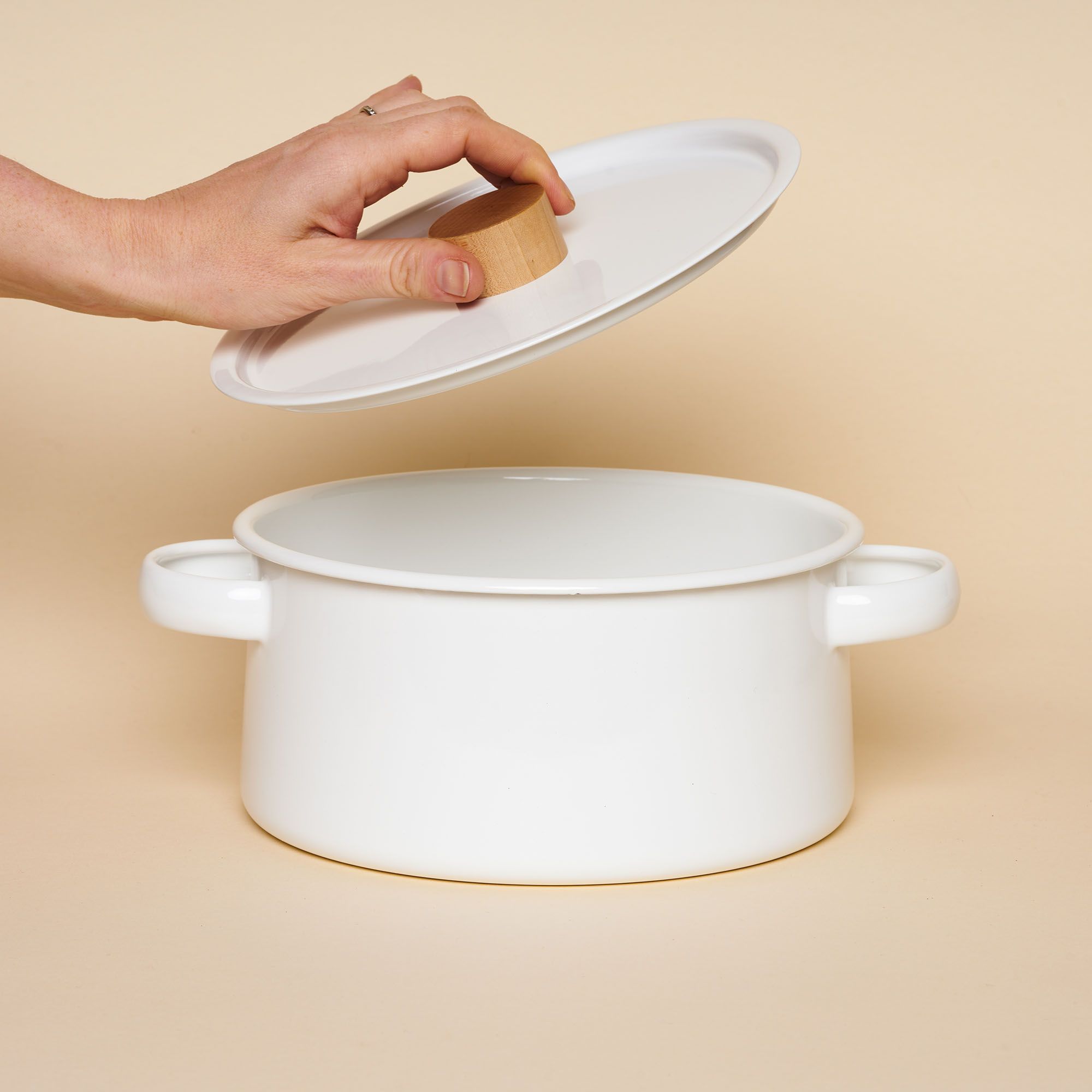 A white enamel pot with a tapered shape, handles on the side and light wooden handle on top.