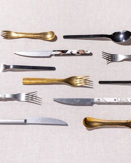 Different styles of forks, spoons, and knifes artfully lined up in parallel rows.