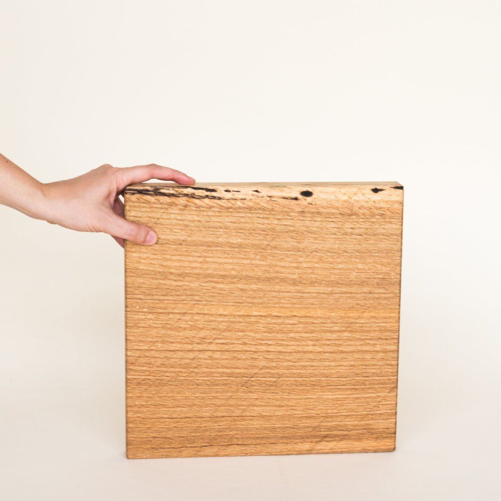 Square light wood cutting board grasped by a hand