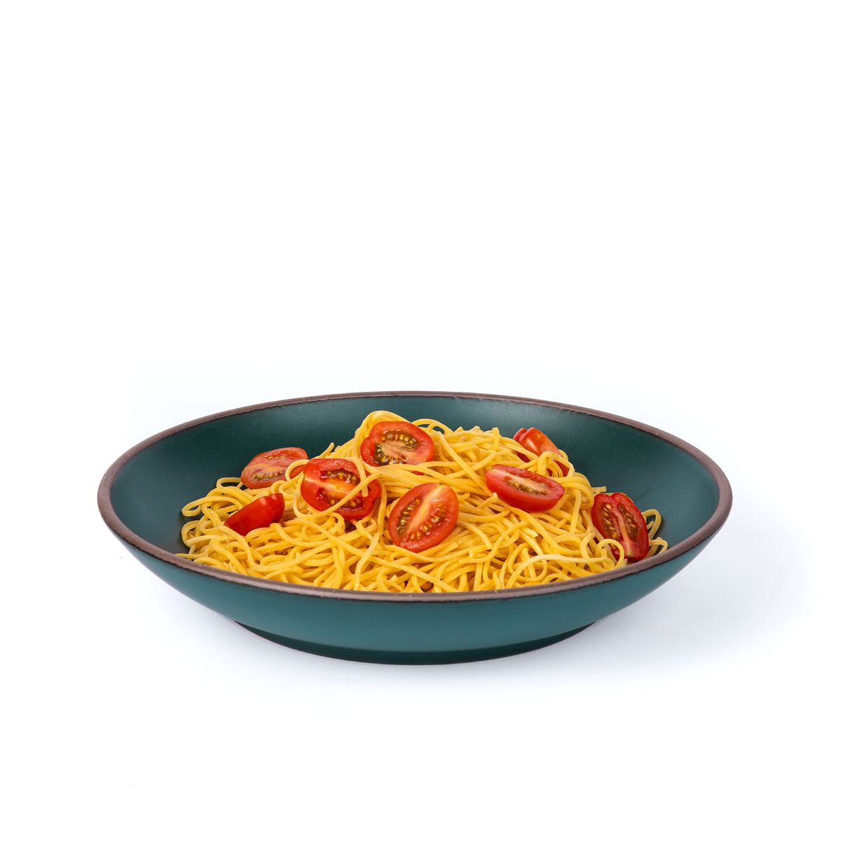 Spaghetti and sliced tomatoes on a large ceramic plate with a curved bowl edge in a deep, dark teal color featuring iron speckles and an unglazed rim.