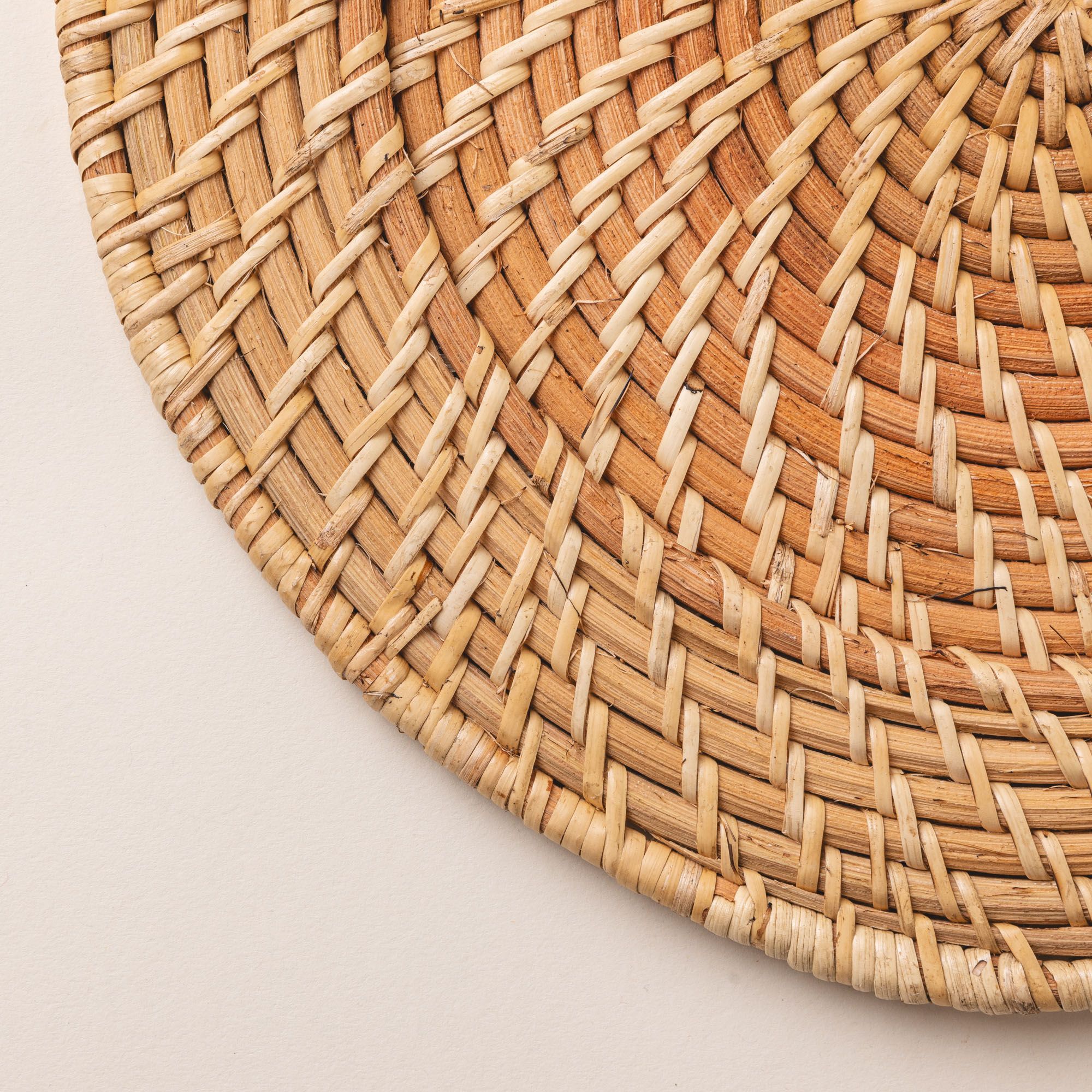 A close up of a natural hand woven dinner plate charger.