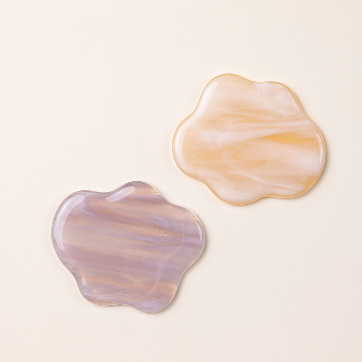 2 glass coasters shaped like clouds in a peach and earthy pink color