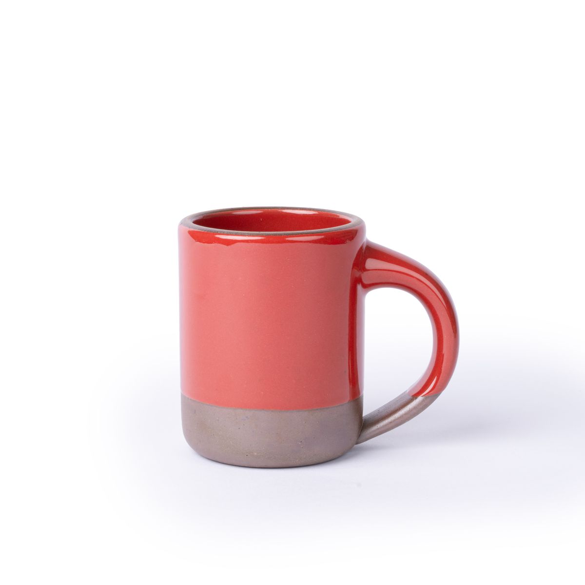 A medium sized ceramic mug with handle in a glossy red color featuring iron speckles and unglazed rim and bottom base.