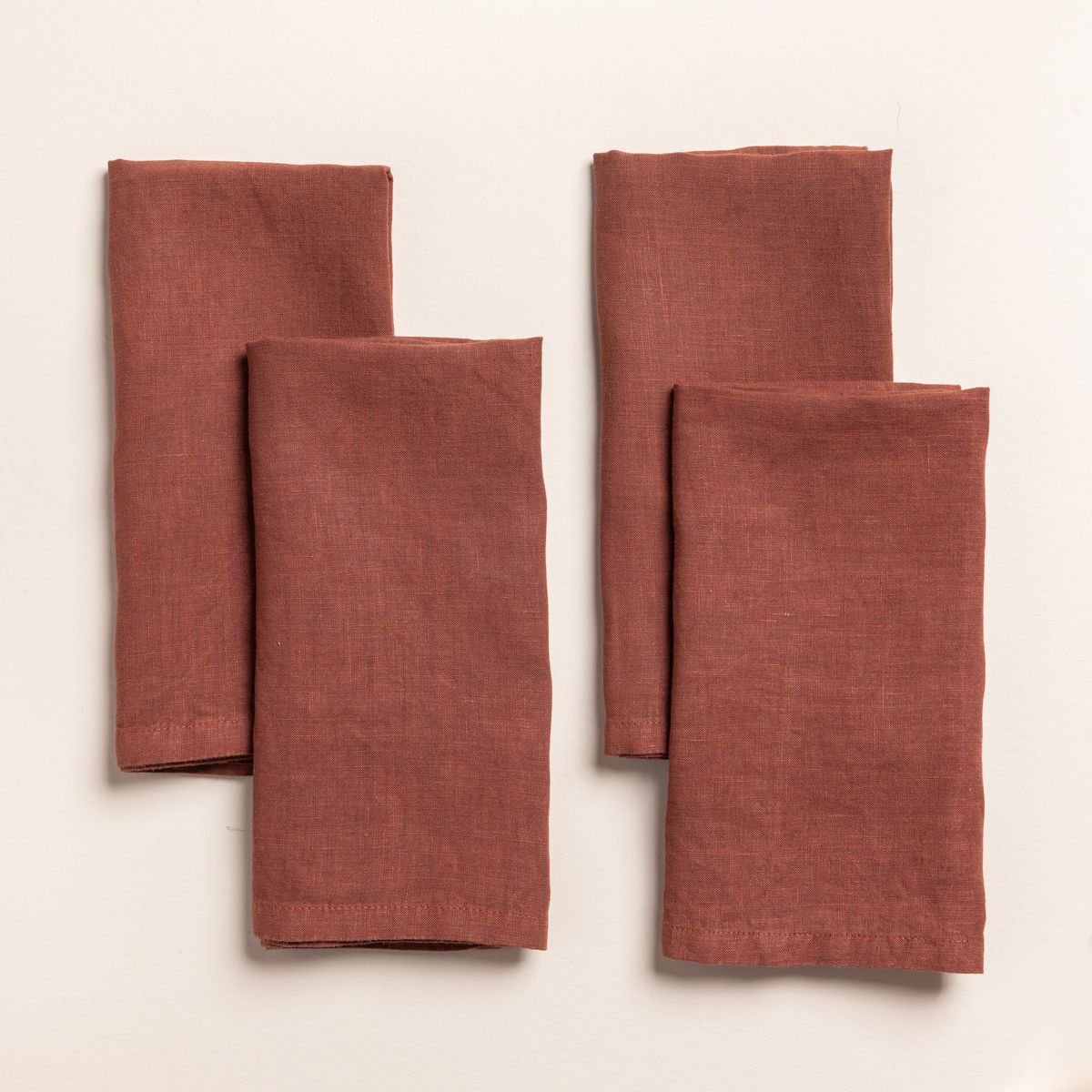 4 folded linen napkins in a terracotta color