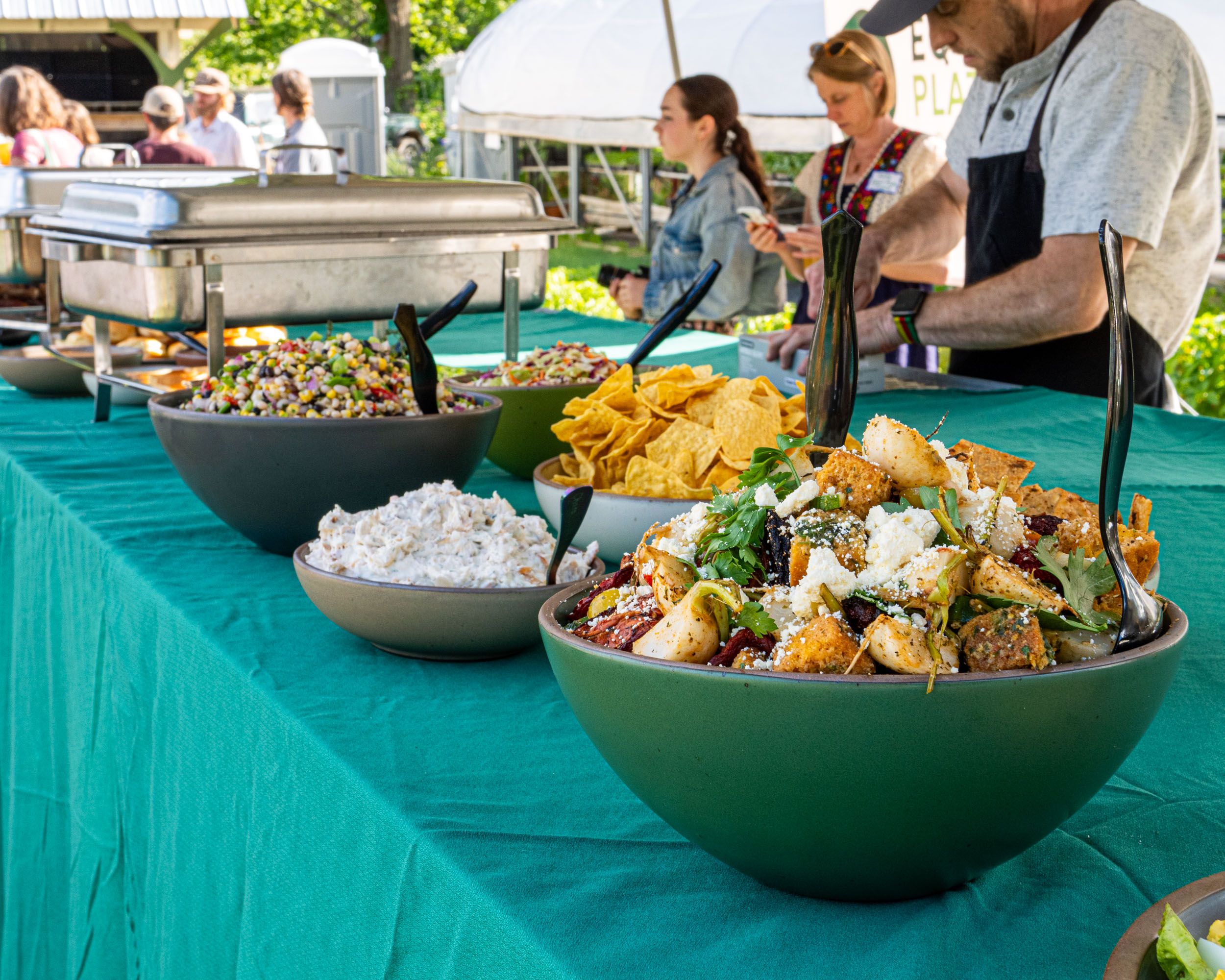 On an outdoor table, fresh foods are ready to serve in a variety of ceramic bowls