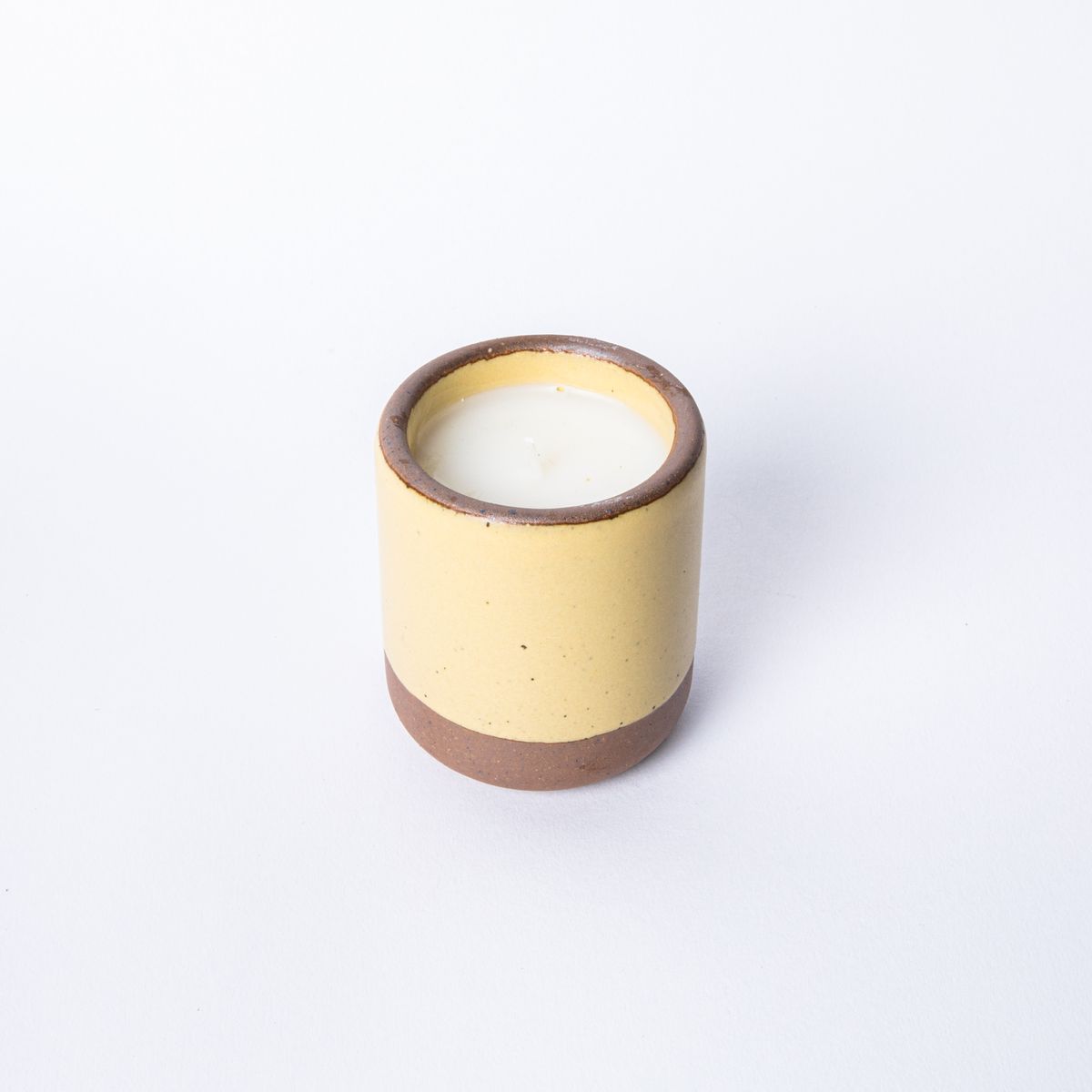 Small ceramic vessel in soft butter yellow color with candle inside
