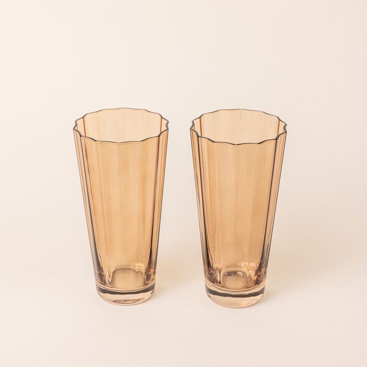 Two tall transparent light amber glasses with wide grooves on the side