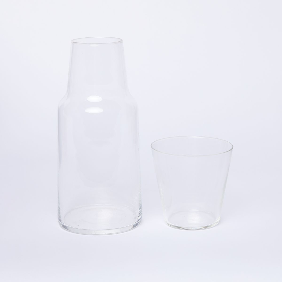 Clear glass carafe with clear glass next to it