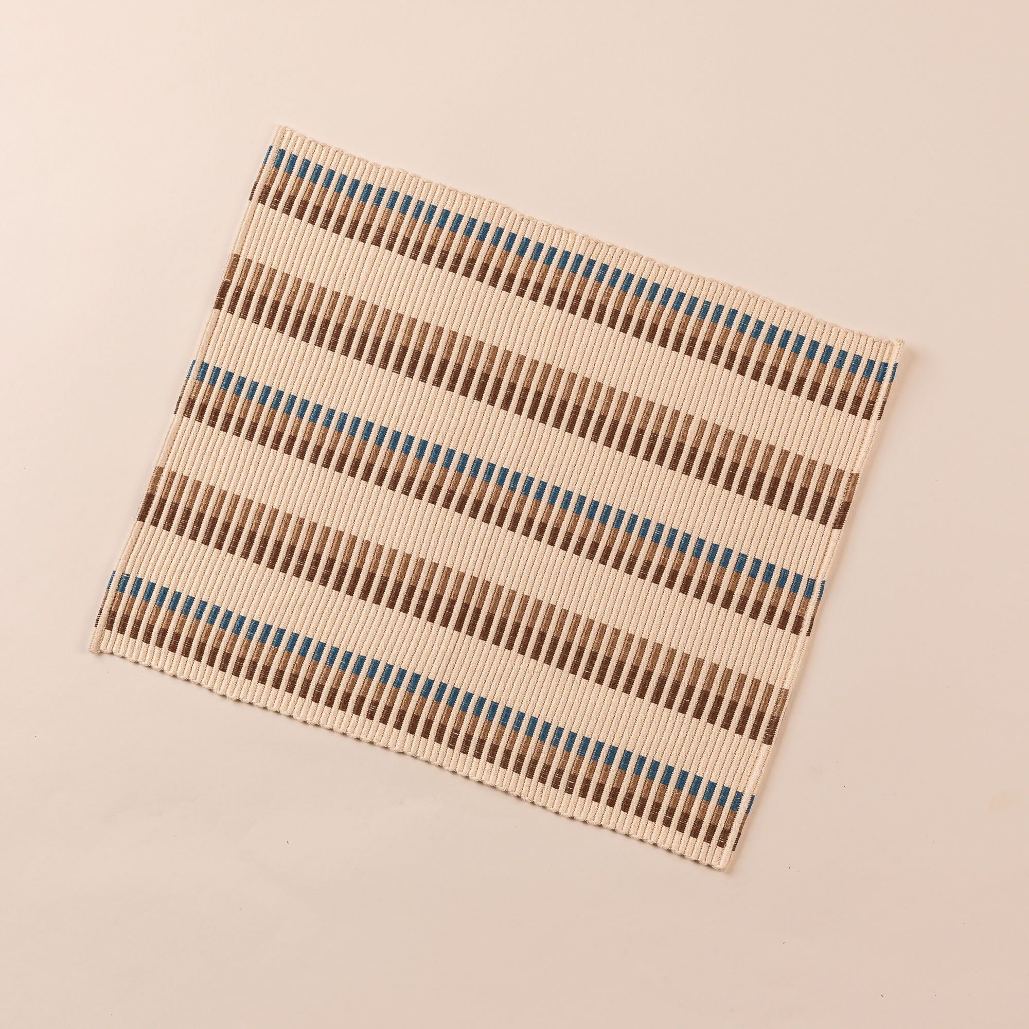 Rectangle placemat with offset stripe design that is hand woven in cream, brown, tan, and blue colors