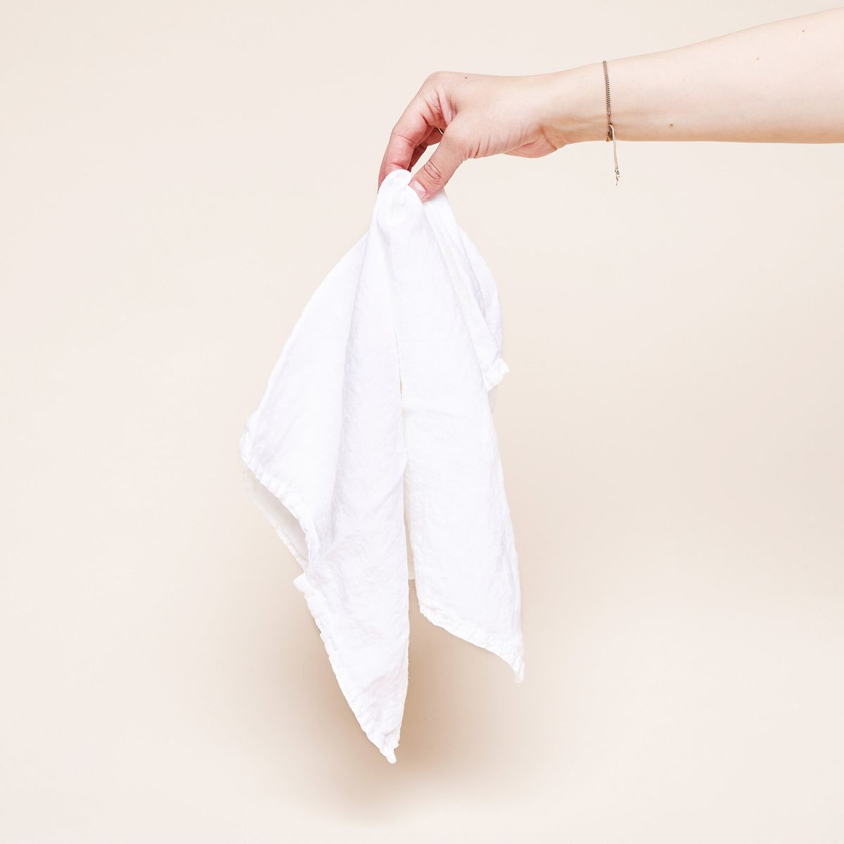 A white linen napkin held loosely by fingers