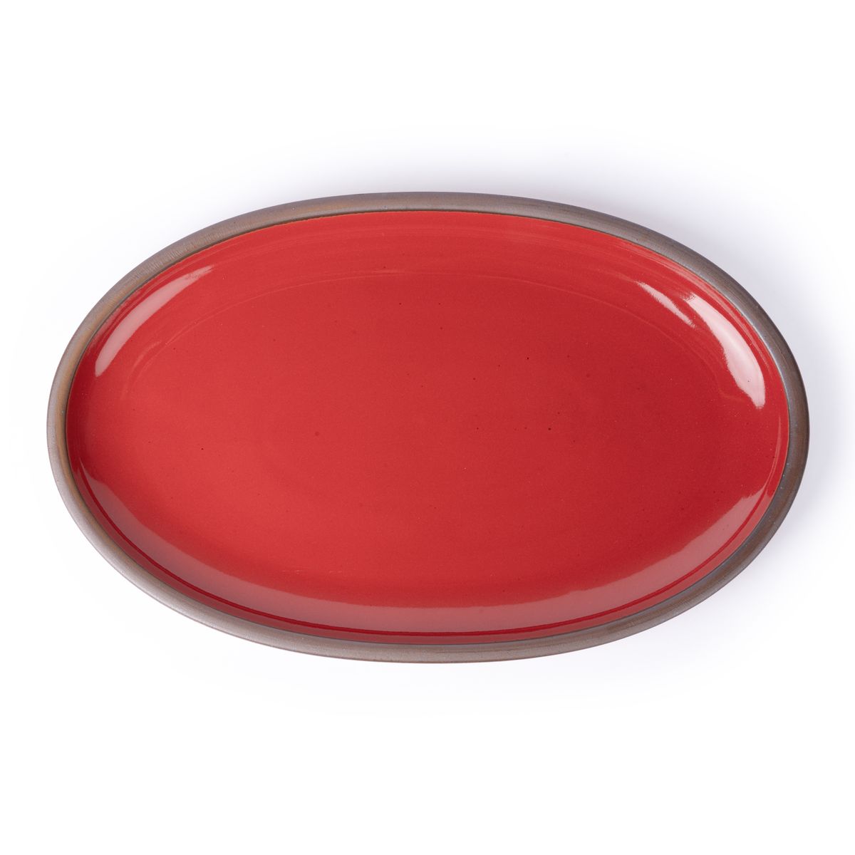 A large oval ceramic platter in a glossy red color featuring iron speckles and an unglazed rim