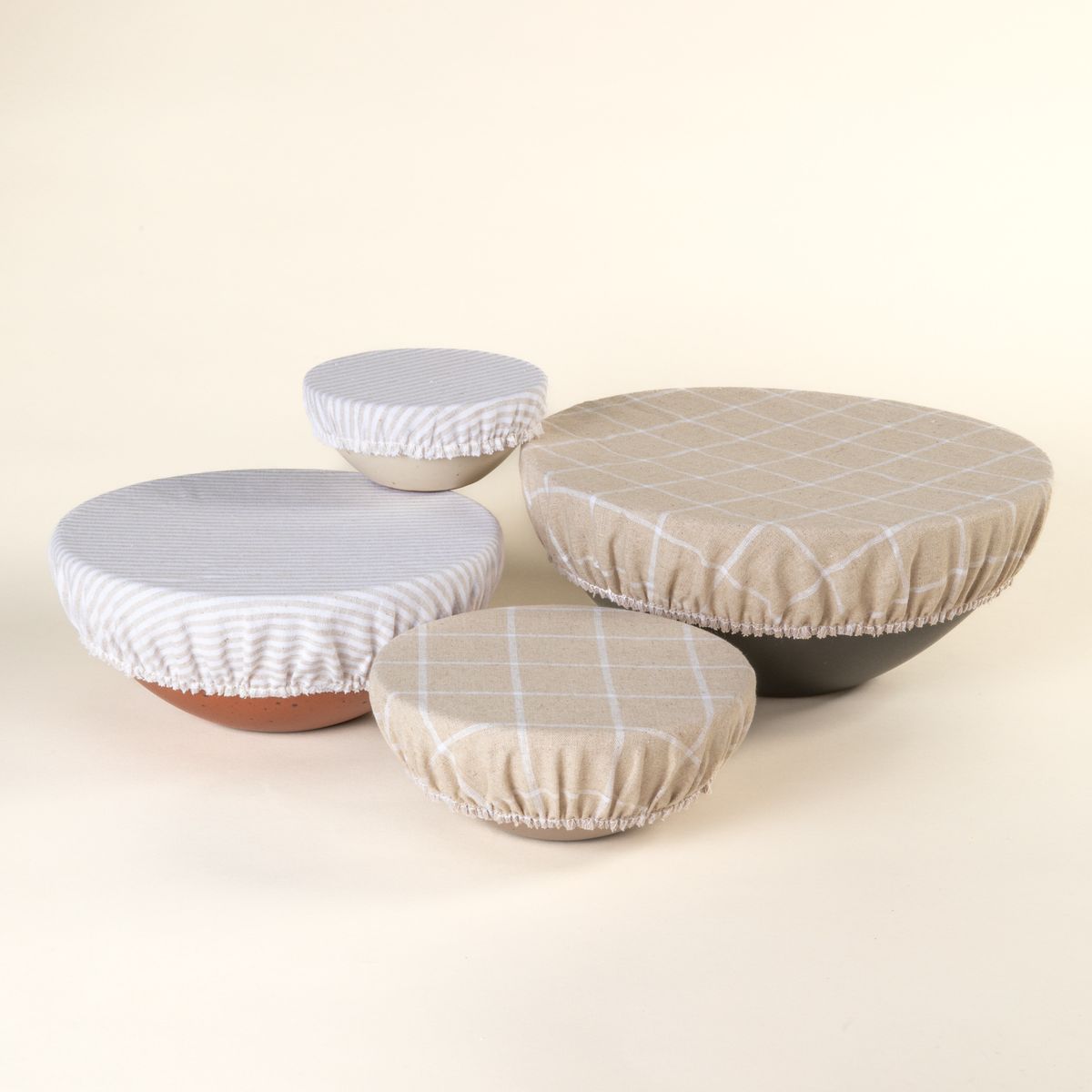 Mixing bowl, popcorn bowl, soup bowl, and ice cream bowl with linen bowl covers on them in neutral and cool white patterns.
