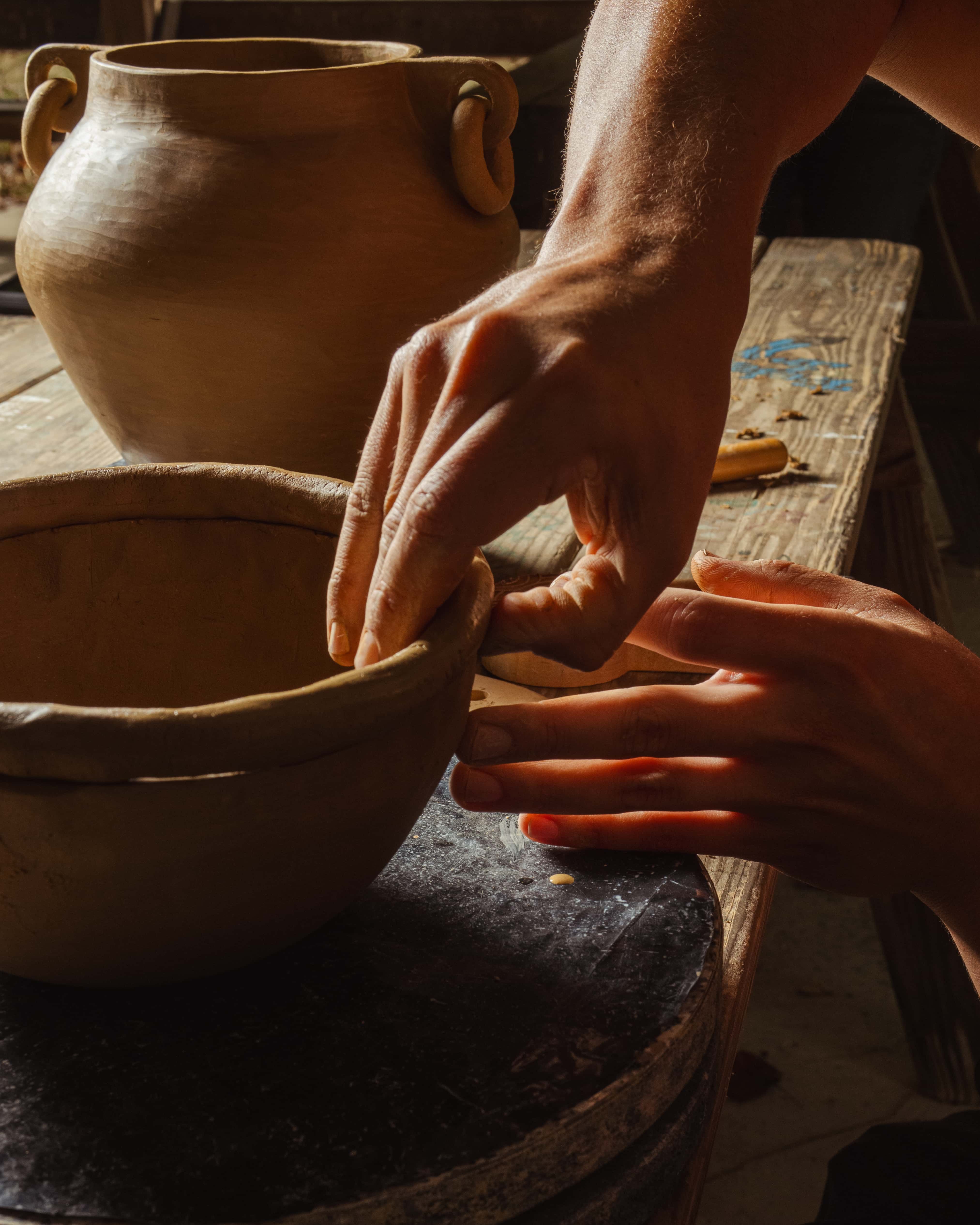 A closeup photo of hands working on forming a clay bowl