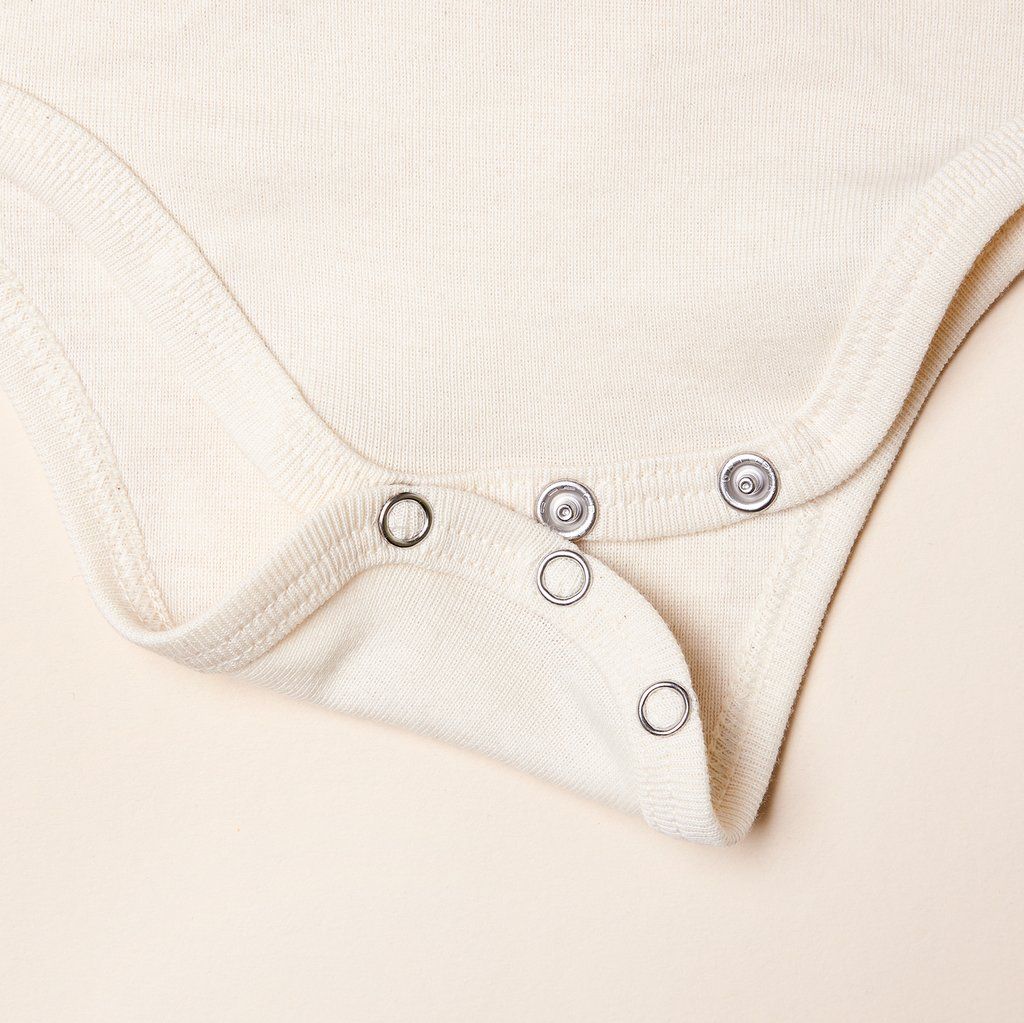 Bottom edge of onesie, showing three silver snaps
