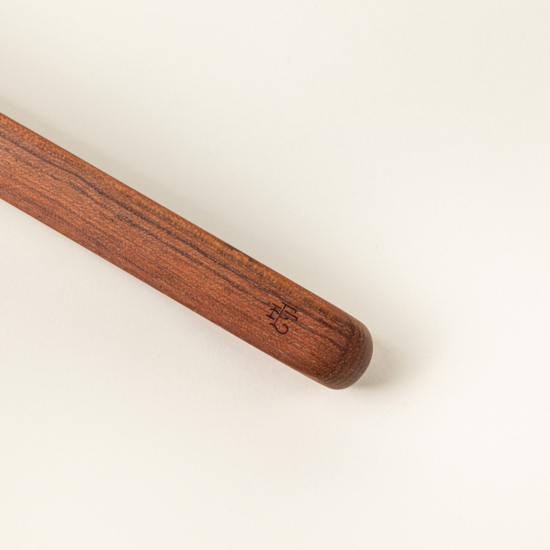 A close up of the end of a simple and minimal wood rectangular tongs, one side reads the East Fork logo