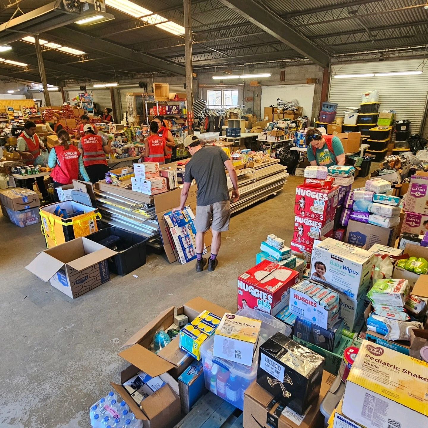 A warehouse filled with boxes of donations and volunteers helping to support Hurricane Helene relief.