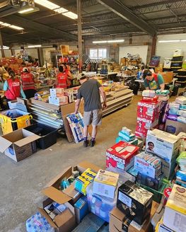 A warehouse filled with boxes of donations and volunteers helping to support Hurricane Helene relief.