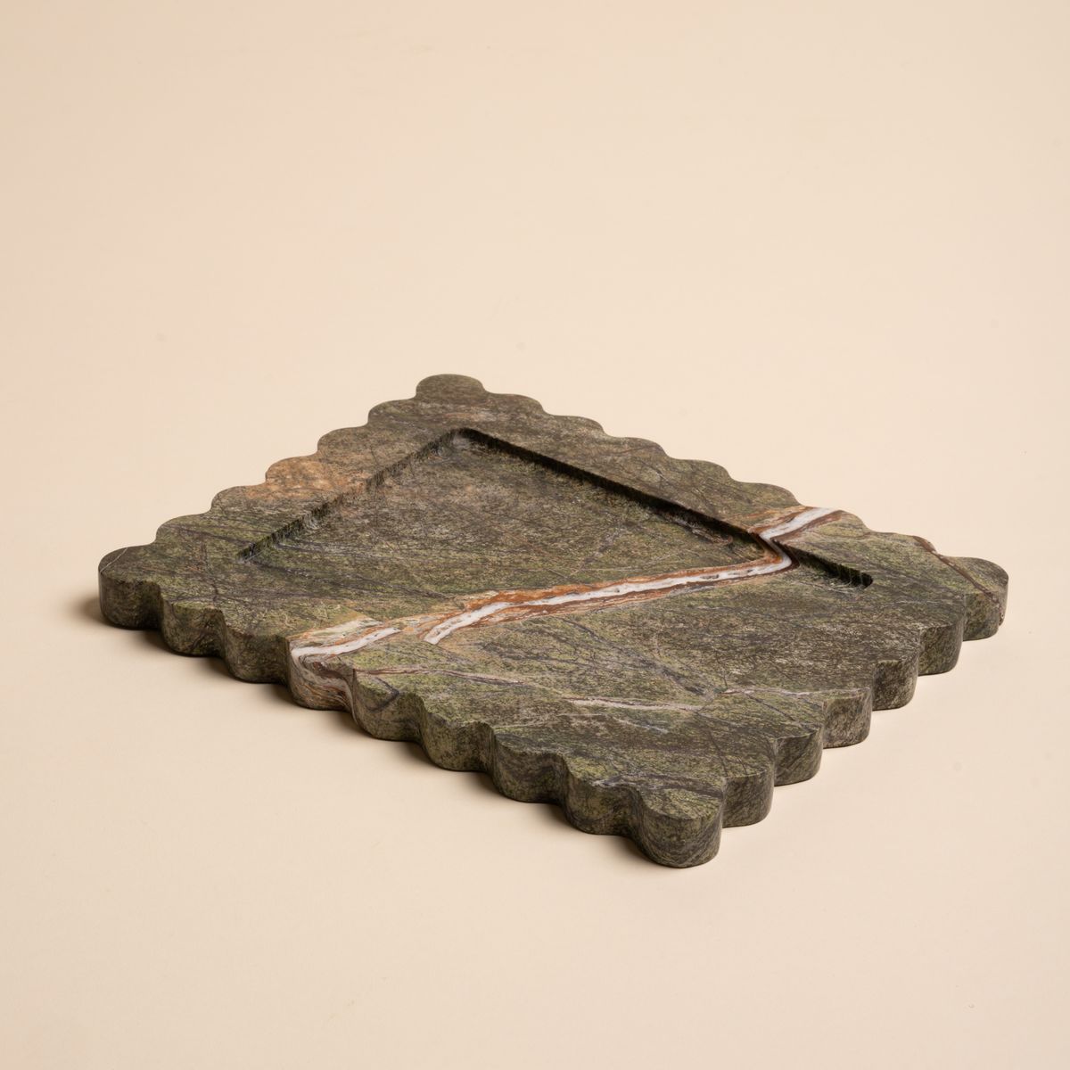 Rectangular green marble tray with scalloped edges and a bold diagonal vein of white and rust running across its surface.
