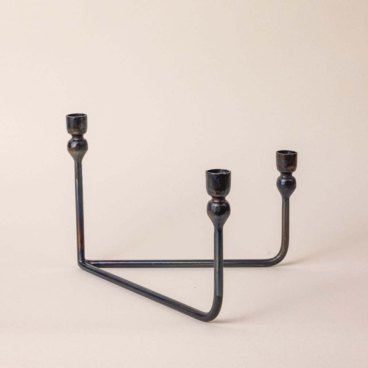 A sophisticated iron candelabra with a v-shaped base and 3 candlestick holders