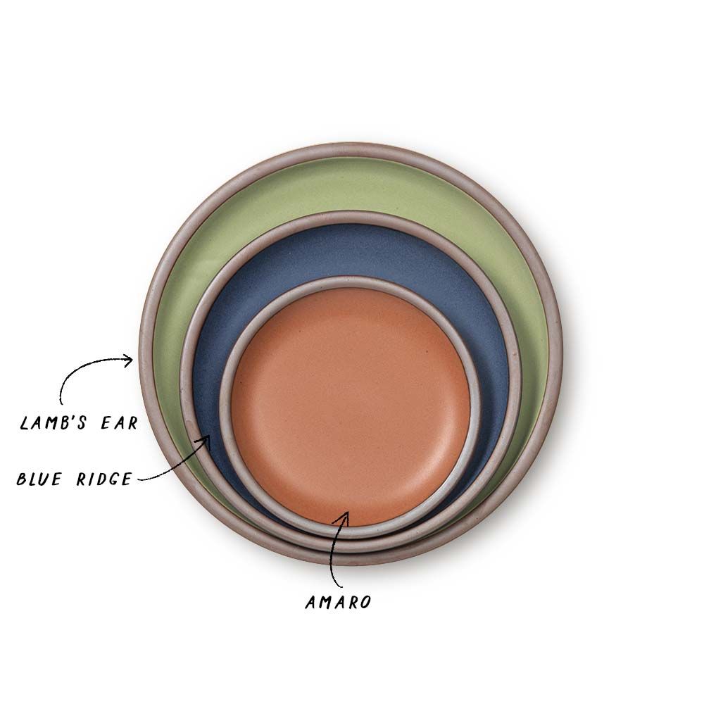 A stack of ceramic plates in a calming sage green, muted navy, and terracotta colors.