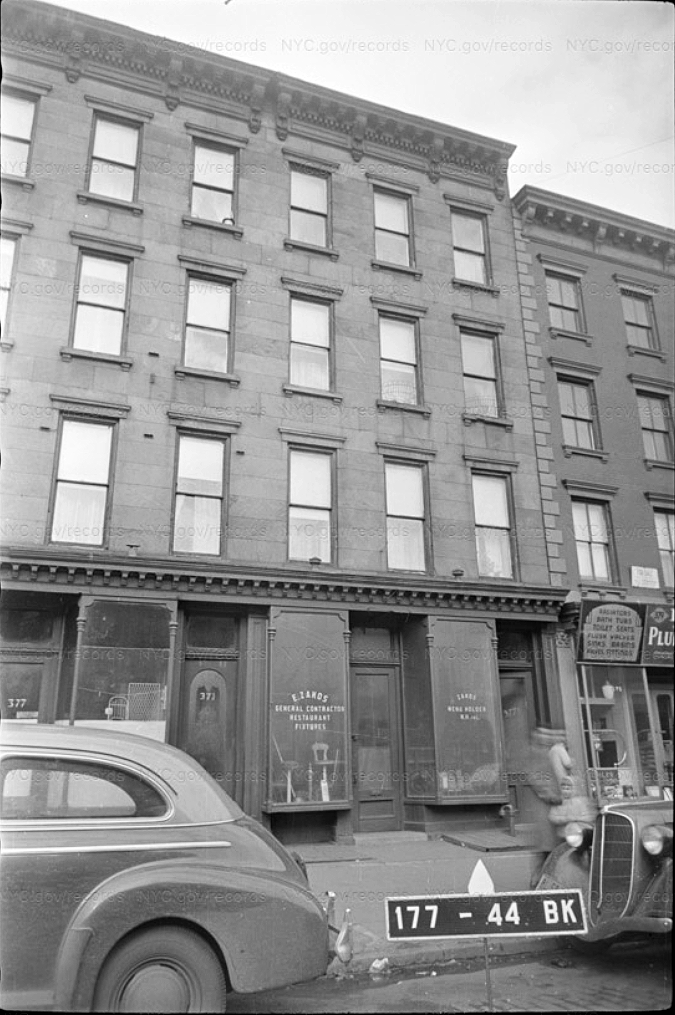 An old black and white photo of the building with old cars outside on the street.