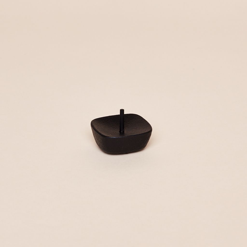 A black square candle holder with a black spike in the center