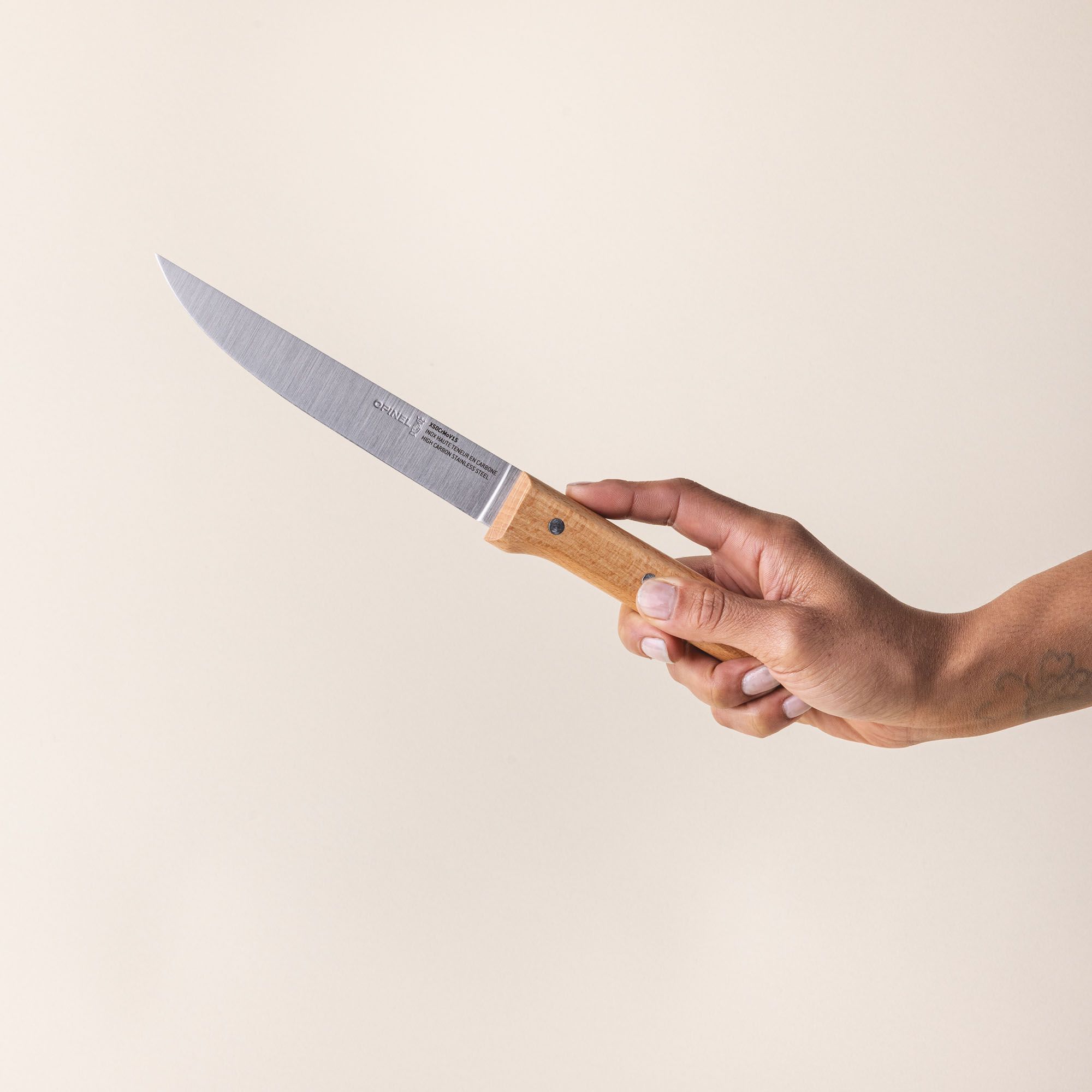 A hand is holding a carving knife with a stainless steel blade and wooden handle