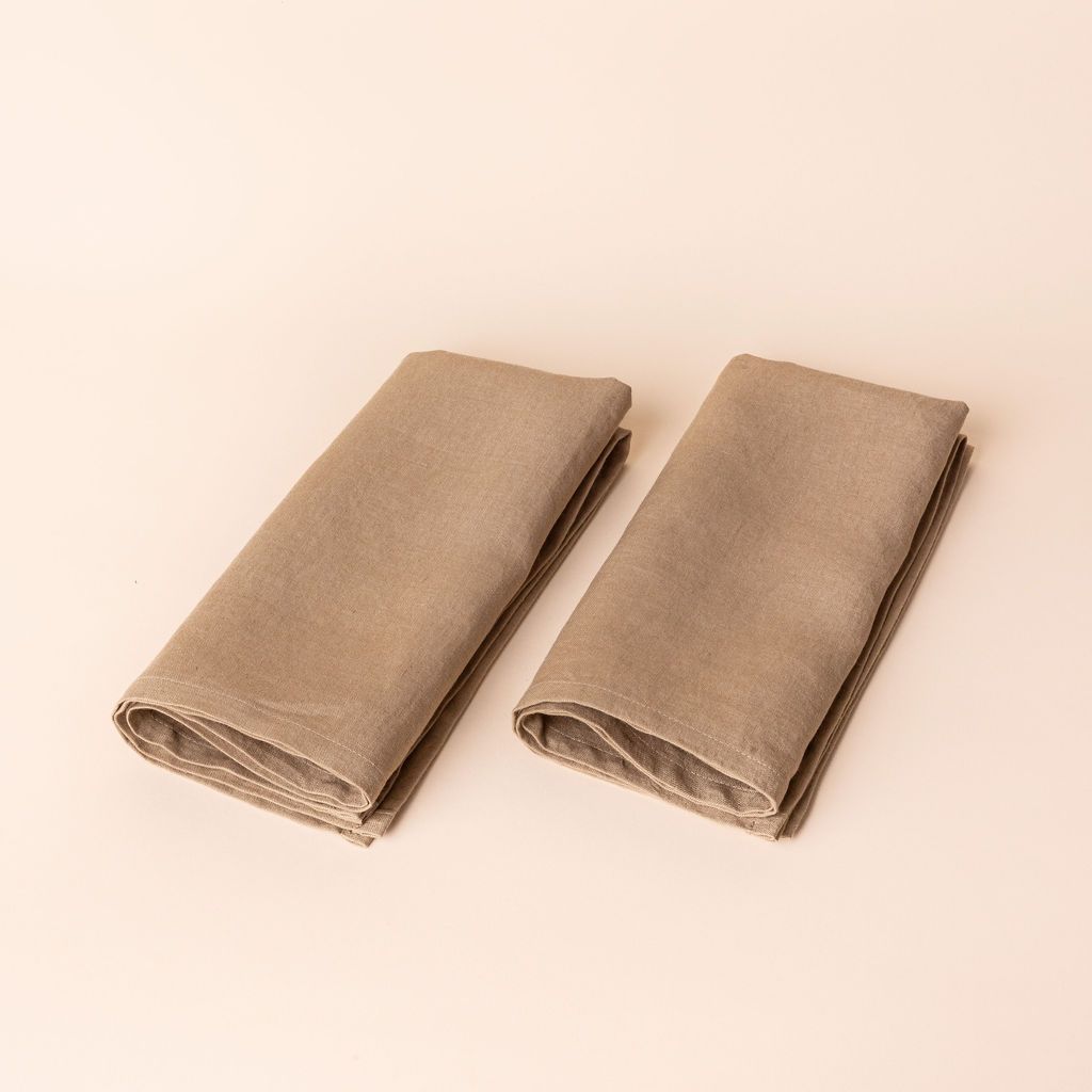 Two soft light brown napkins folded into rectangles side by side