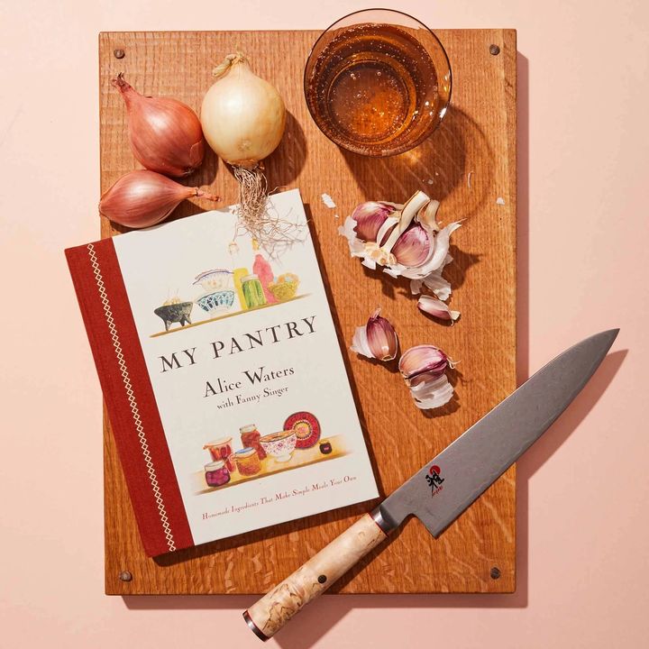 My Pantry Cookbook on a cutting board with knife, garlic and glass