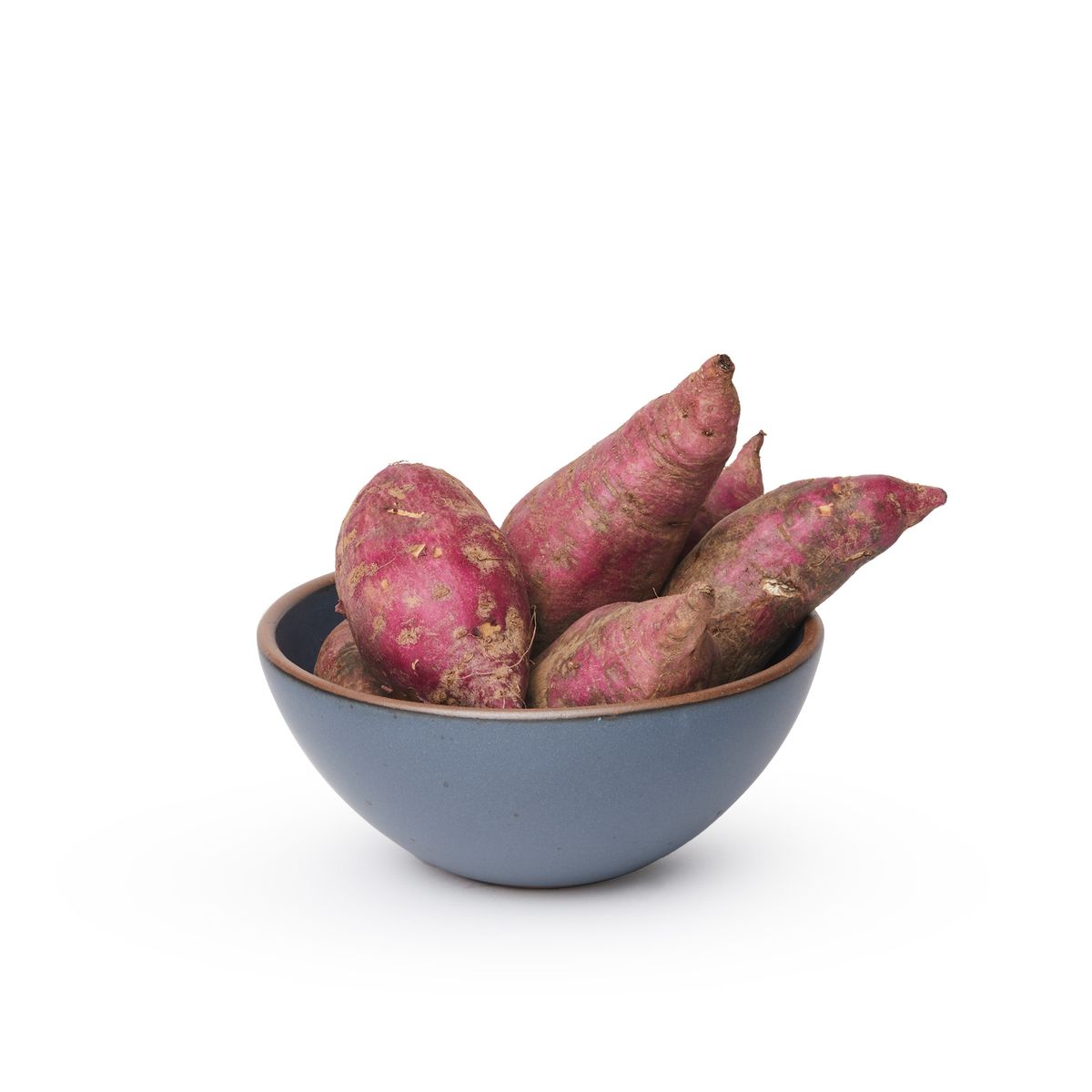 A medium rounded ceramic bowl in a cool, medium blue color featuring iron speckles and an unglazed rim, filled with sweet potatoes