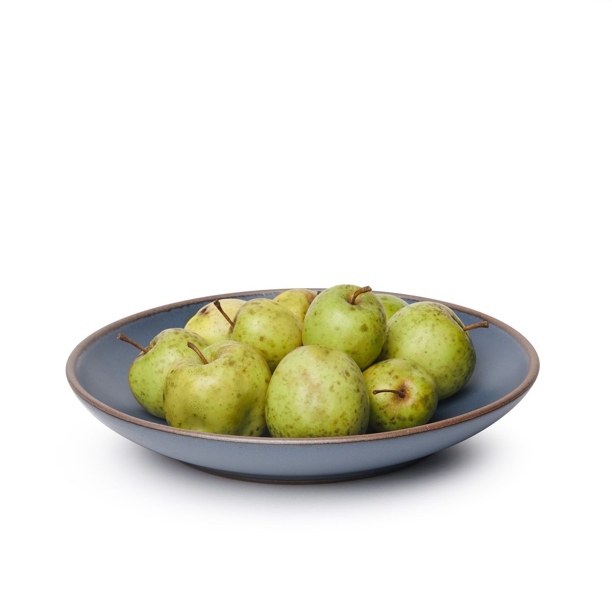 Pears on a large ceramic plate with a curved bowl edge in a cool, medium blue color featuring iron speckles and an unglazed rim.