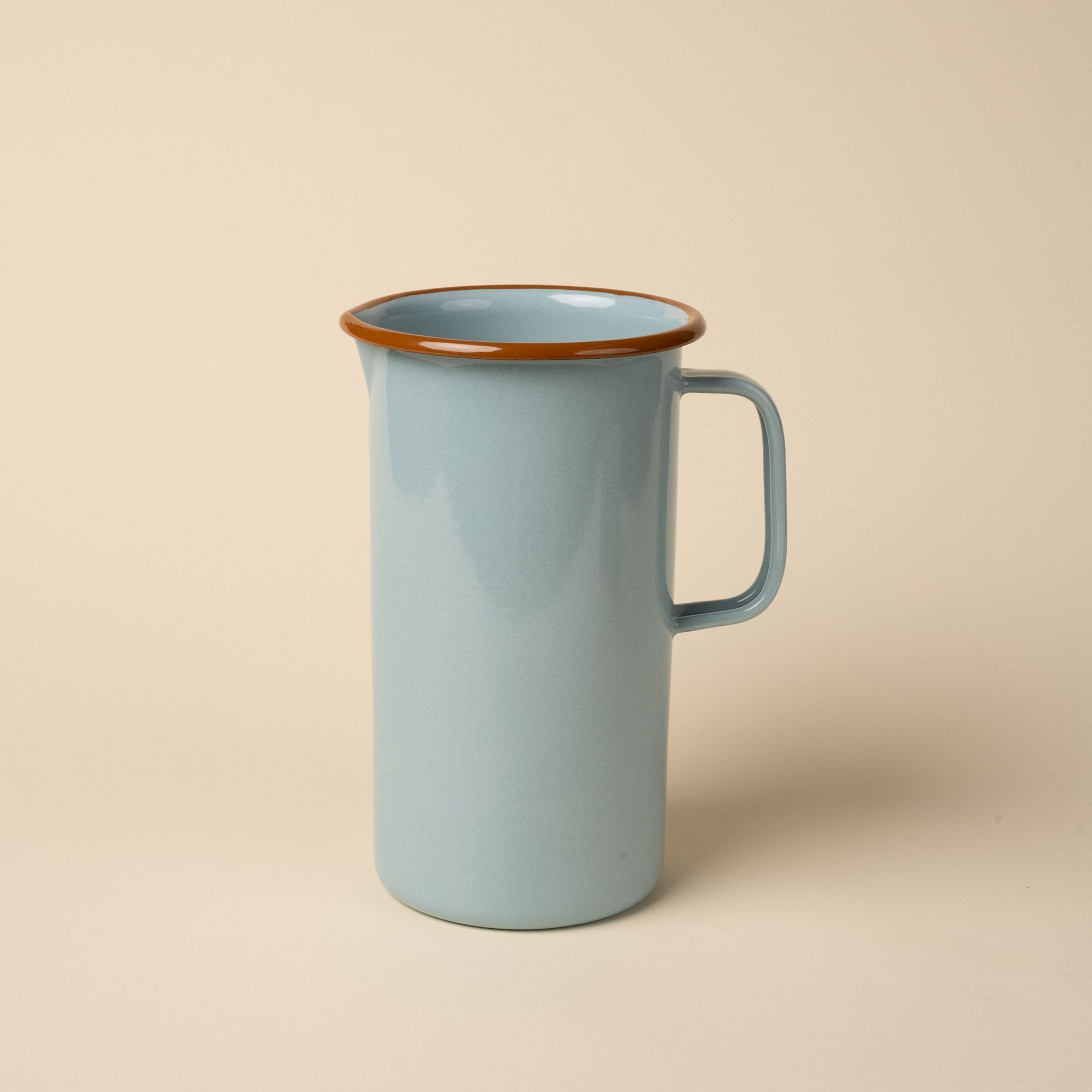 A large enamel pitcher with handle in a robin's egg blue color with a warm brown rim.