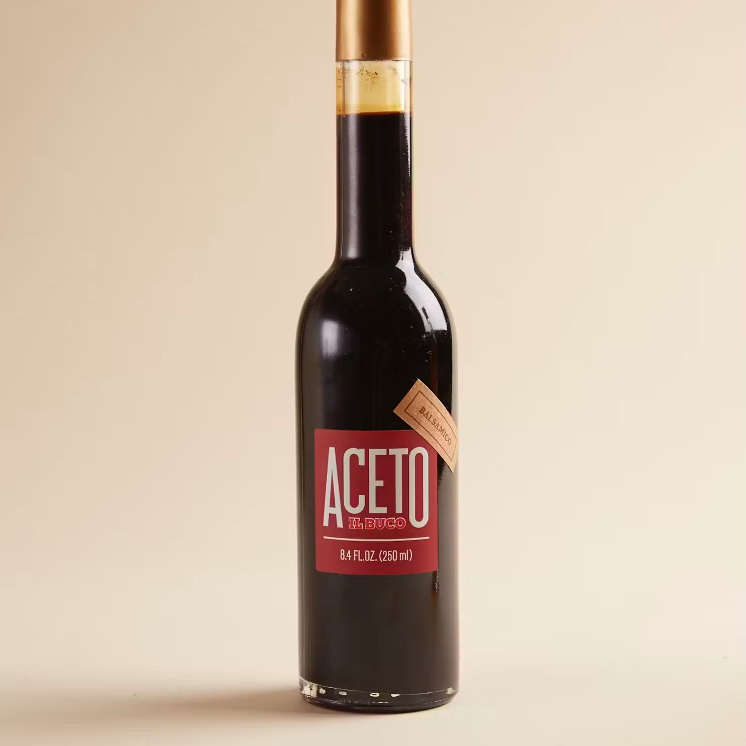 A dark brown narrow bottle with a red label that reads "Aceto Balsamic"