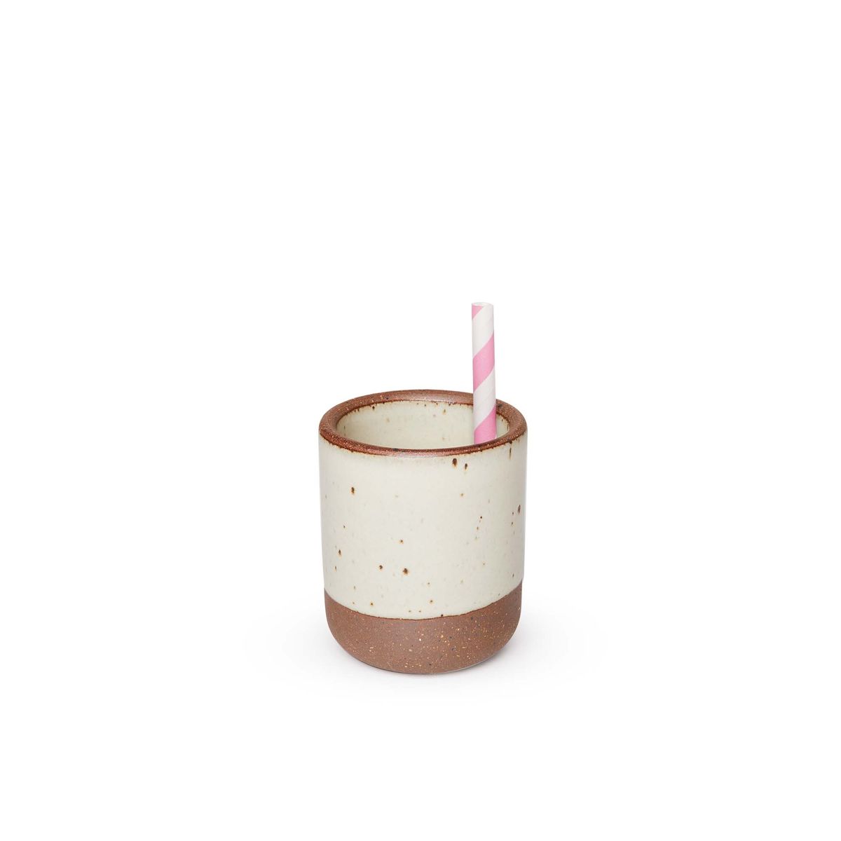 A straw sitting in a small, short ceramic mug cup in a warm, tan-toned, off-white color featuring iron speckles and unglazed rim and bottom base.