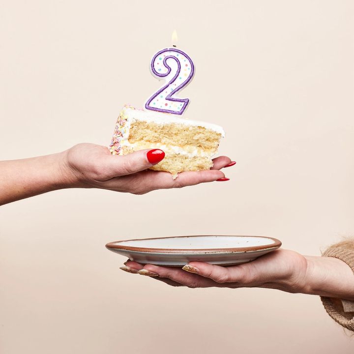 Hand holding cake with 2 candle and cake plate