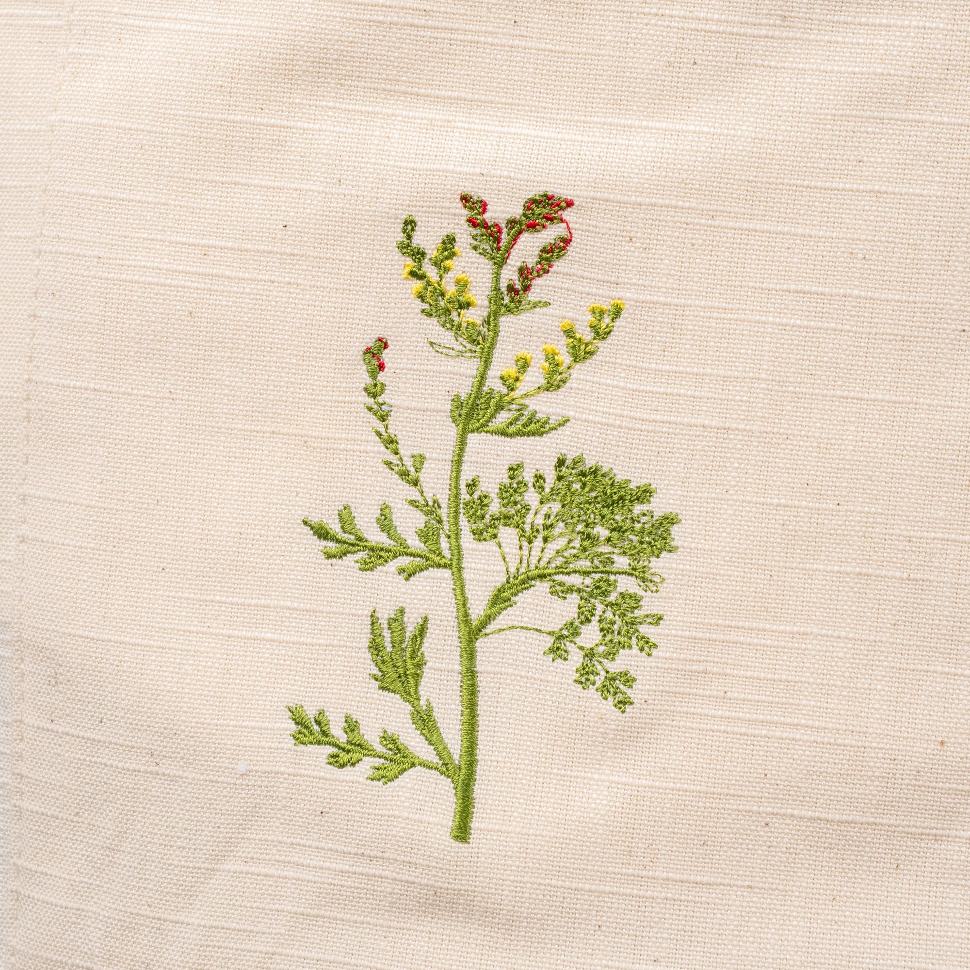 A close up of a green, purple, and yellow embroidered flower on a canvas apron.