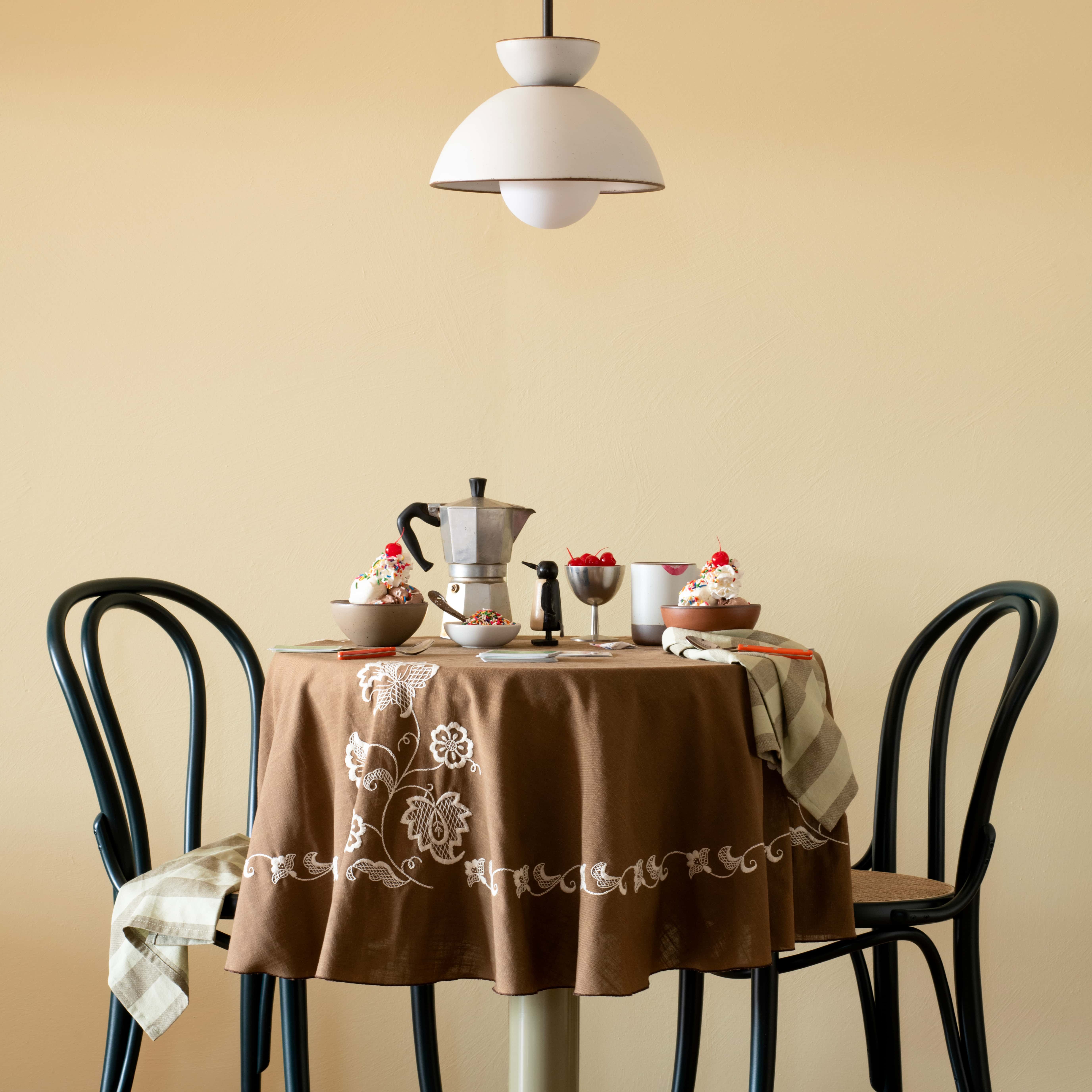 A eggshell light fixture made from East Fork bowls above a table with a tablecloths, espresso pot, and several bowls