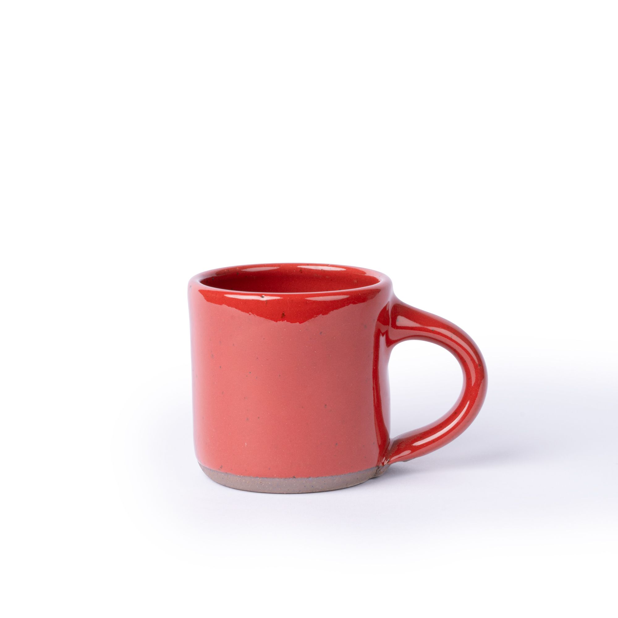 A medium sized ceramic mug with handle in a glossy red color featuring iron speckles