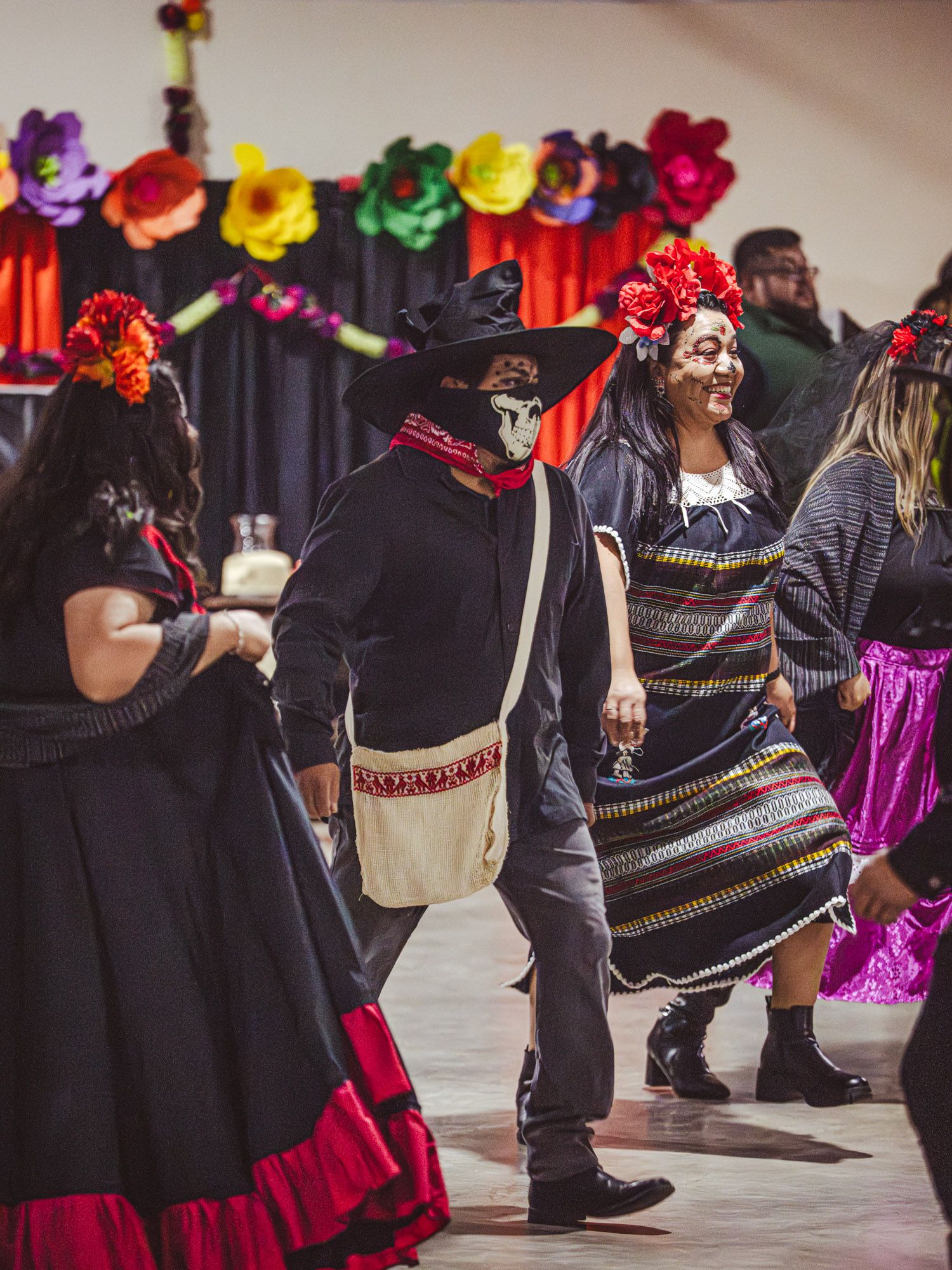 People wearing face paint and masks dancing together at an indoor festival