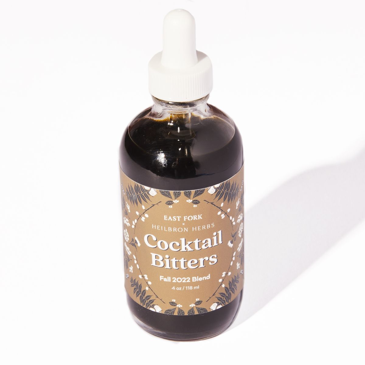 Small clear dropper bottle with liquid and a gold label that reads 'Cocktail Bitters'