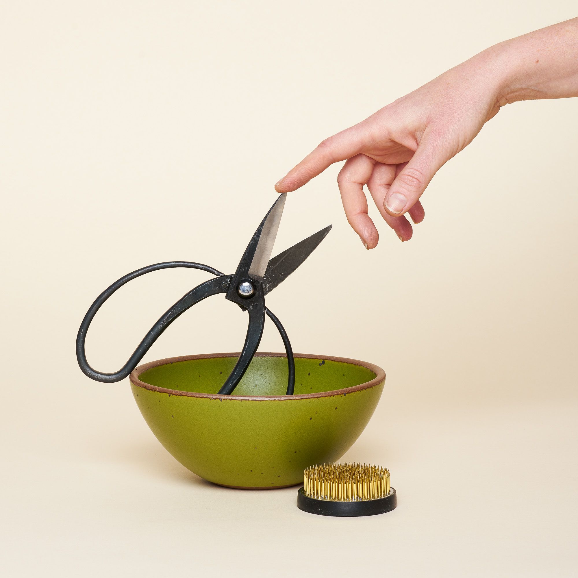 A set that comes with gardening shears, a green East Fork bowl and a "Flower Flog," a small circular dish with spikes used to construct floral arrangements and keep flowers in place. Flower frogs sit inside the floral container in the water and are traditionally known for their use in ikebana, the Japanese art of floral design.