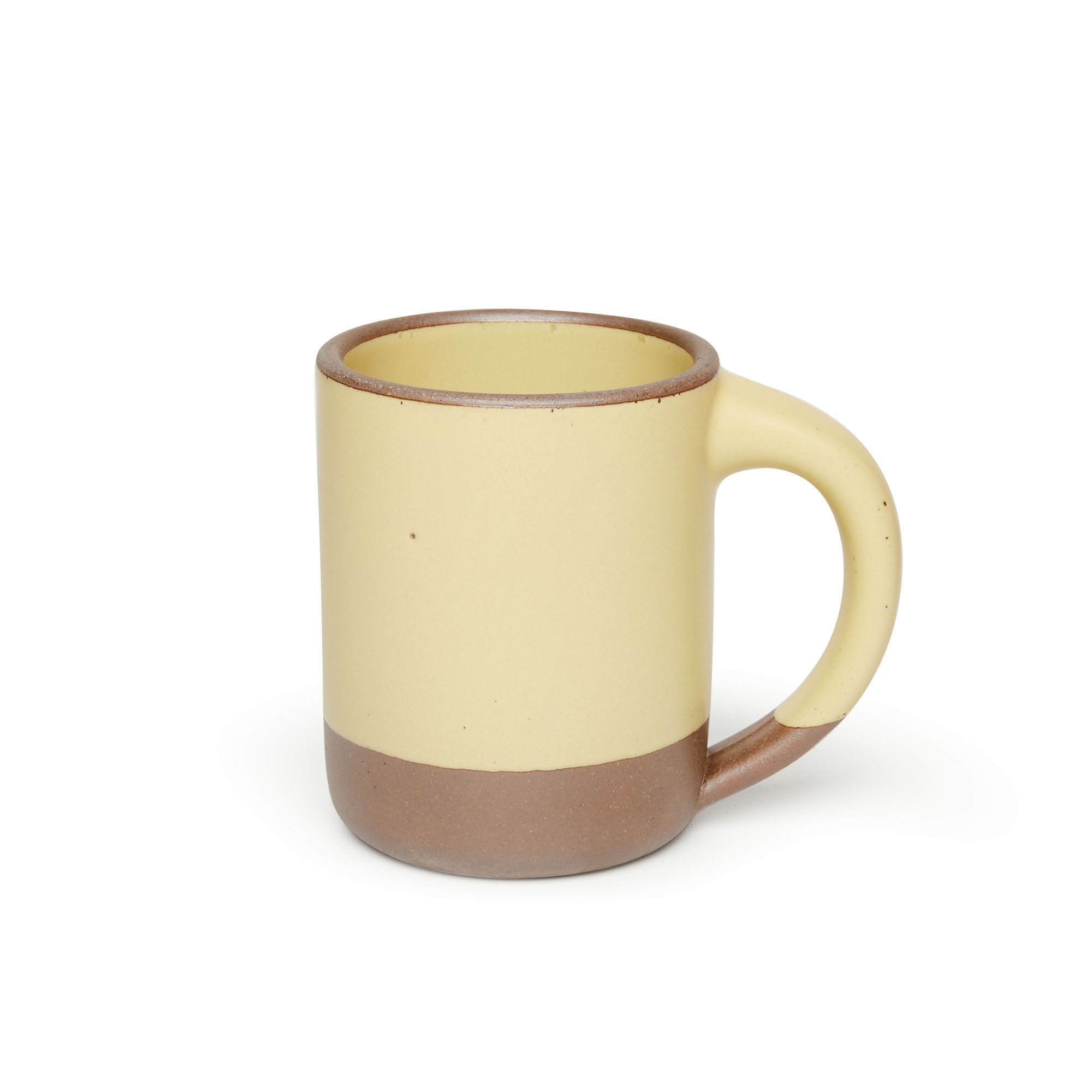 A big sized ceramic mug with handle in a light butter yellow glaze featuring iron speckles and unglazed rim and bottom base.