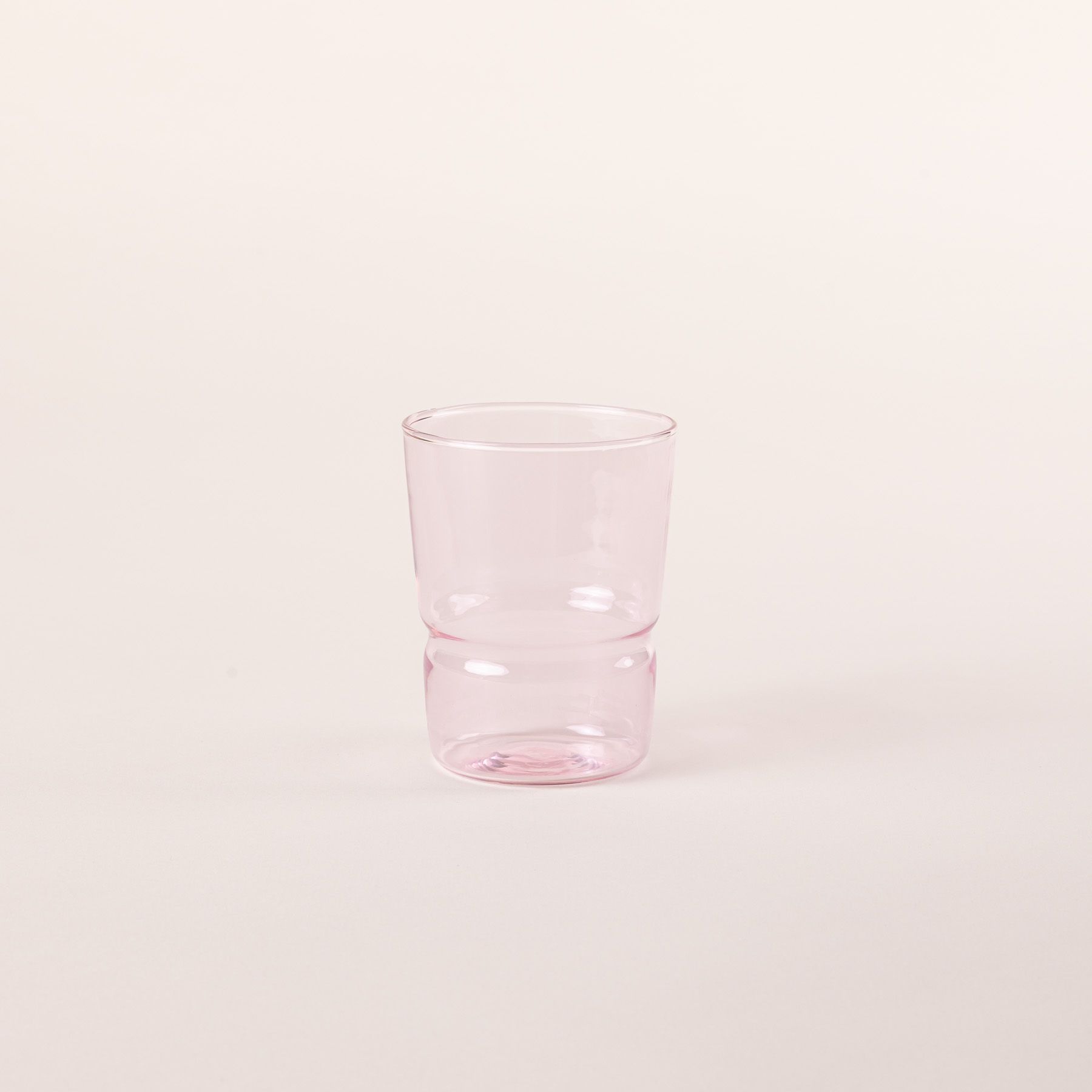 Tumbler glass that widens at the top in a soft pink color