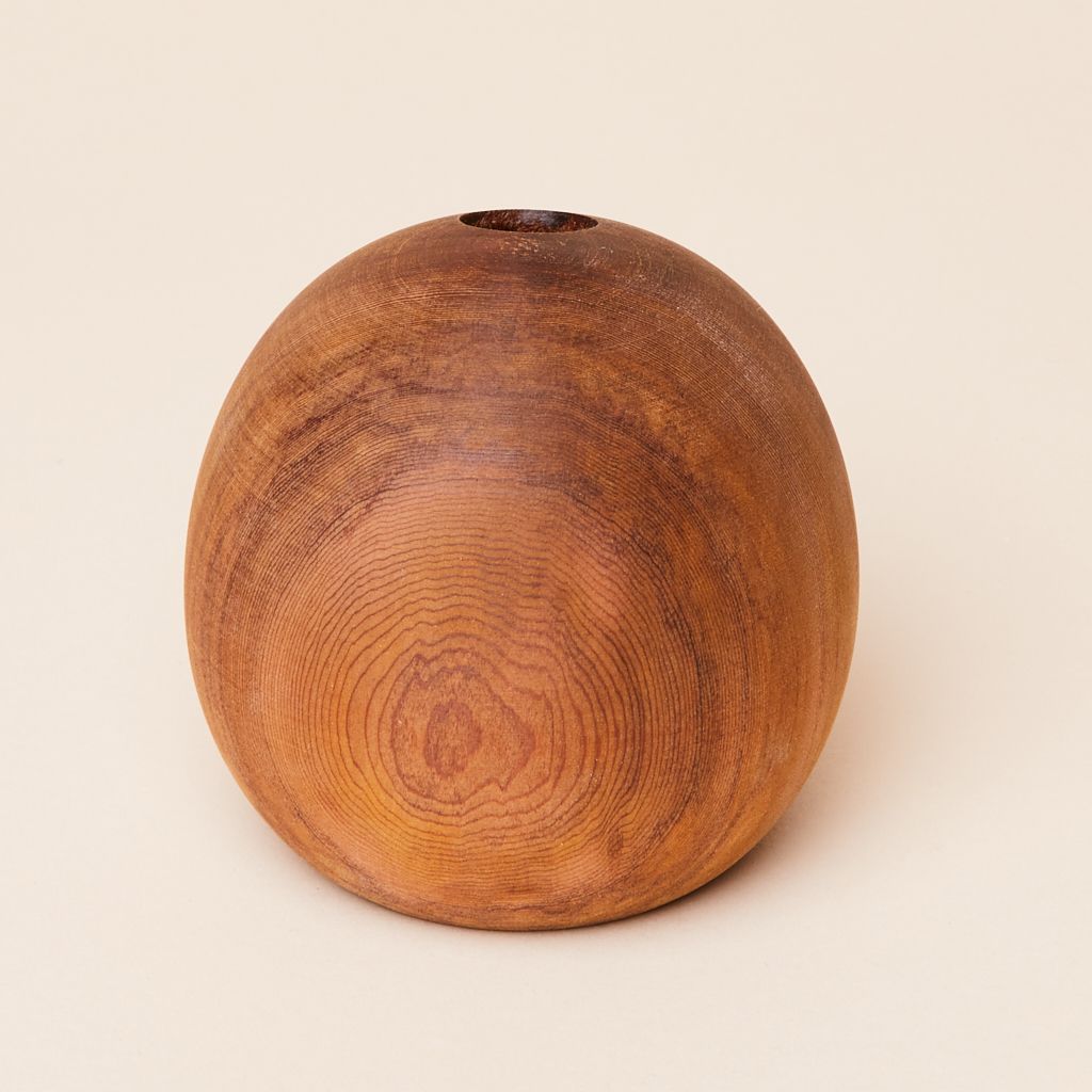 An elongated sphere of wood that has a pattern of grain and a circular hole at the top