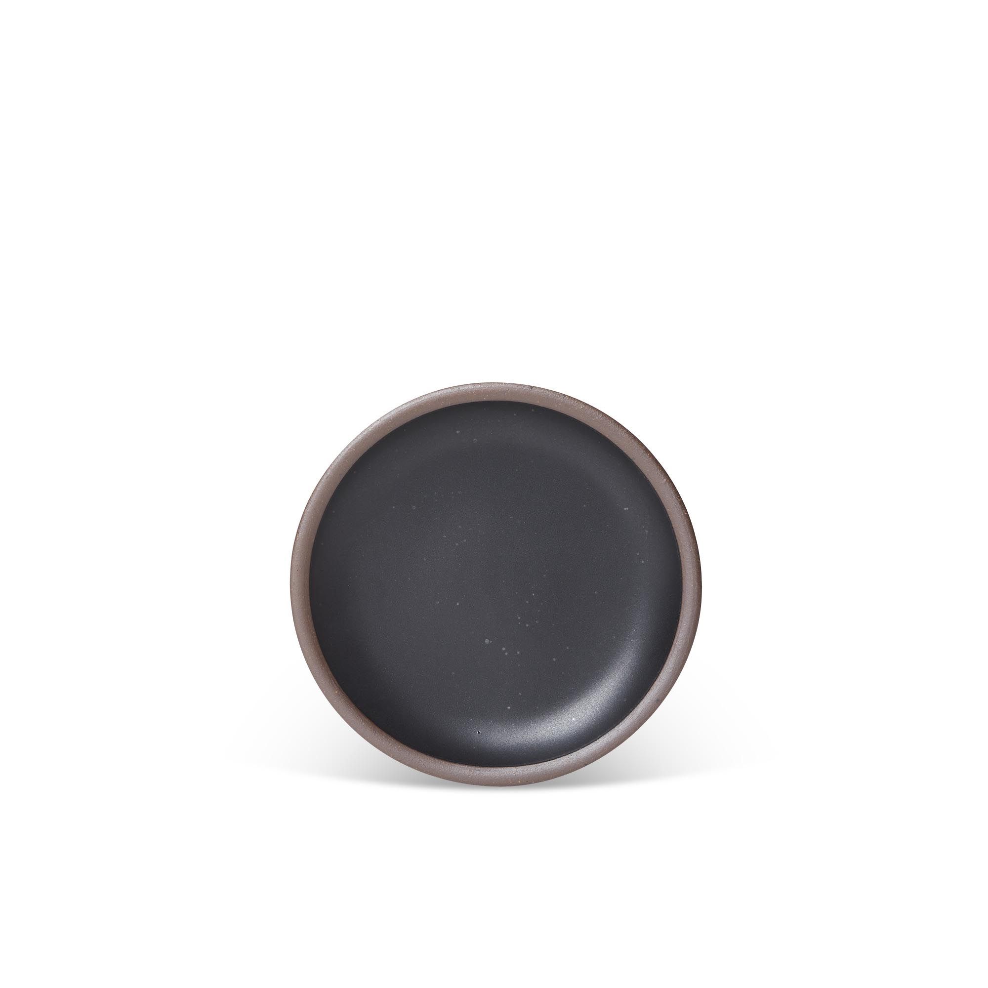 A dessert sized ceramic plate in a graphite black color featuring iron speckles and an unglazed rim.
