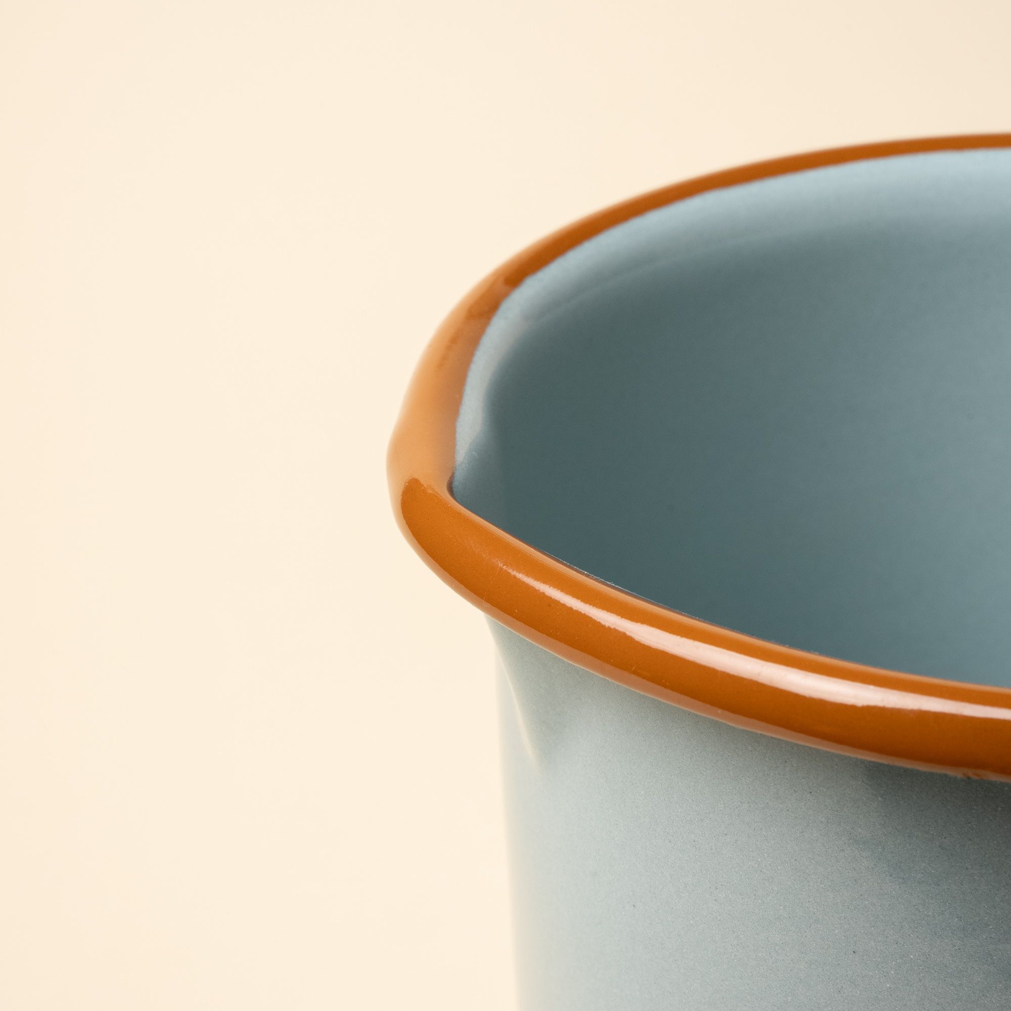 A closeup of the spout of an enamel pitcher.