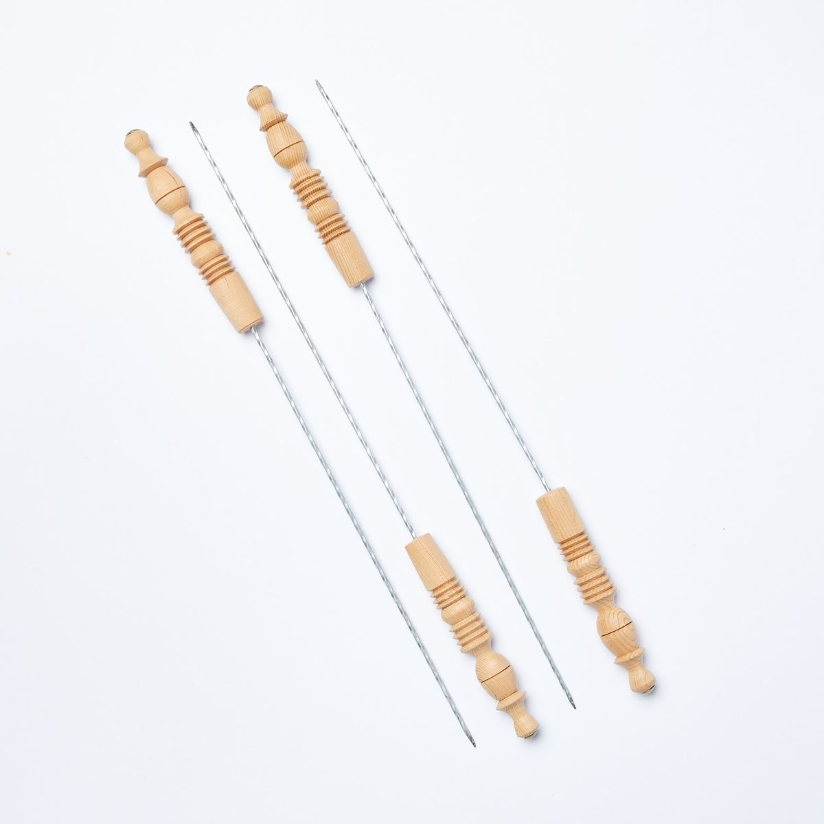 Four metal skewers with wood handles resting on a diagonal