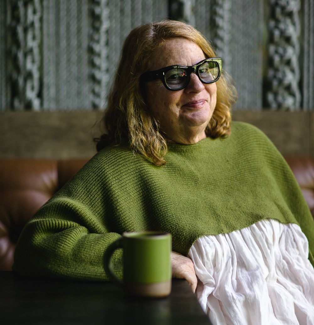Chef and restaurateur Anne Quatrano wearing a fern green sweater with a matching mug on the table.