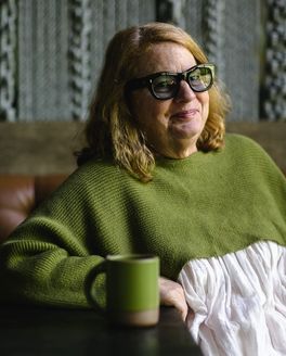 Chef and restaurateur Anne Quatrano wearing a fern green sweater with a matching mug on the table.